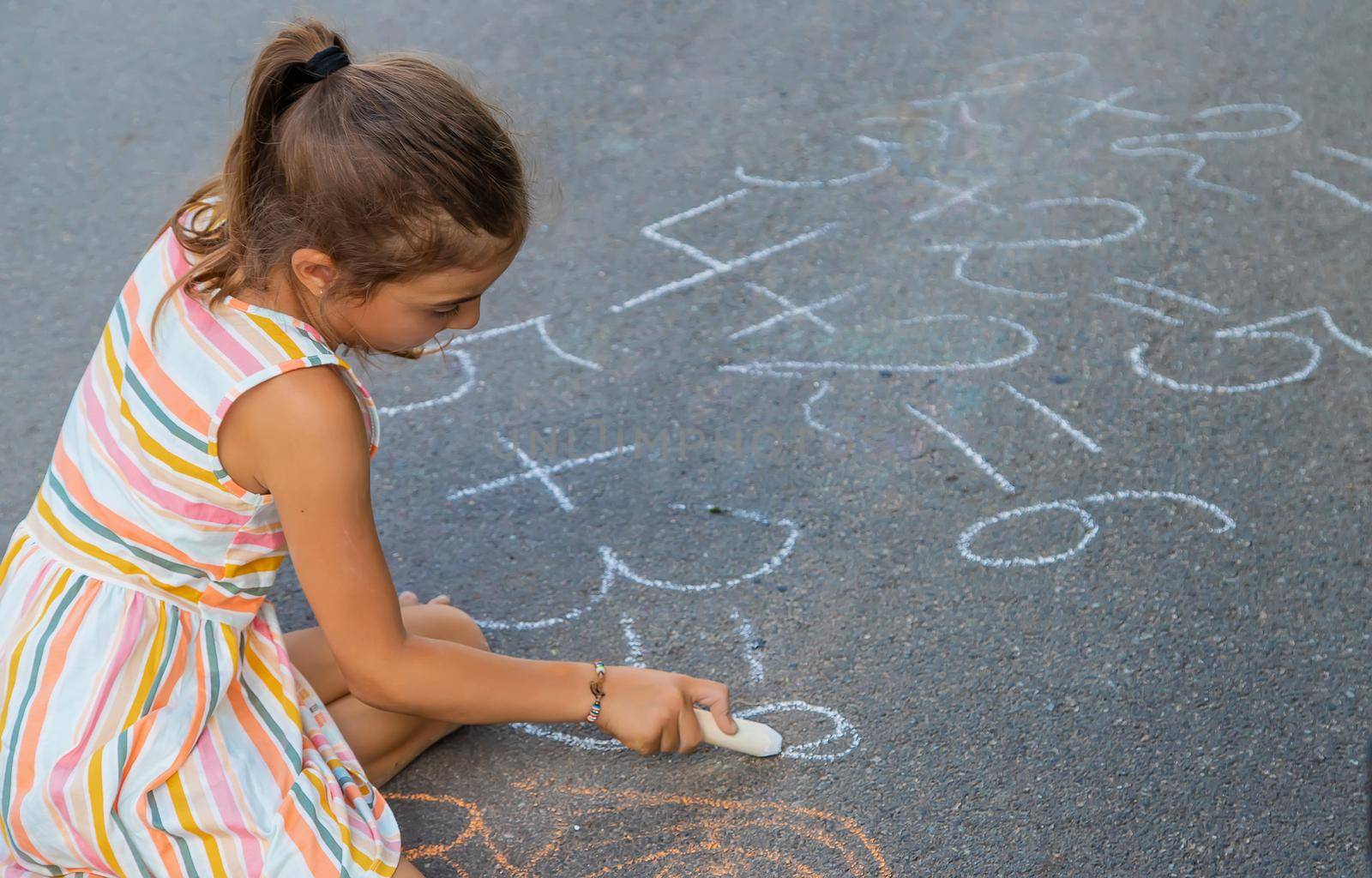 The child is doing chalk lessons on the asphalt. Selective focus. by yanadjana