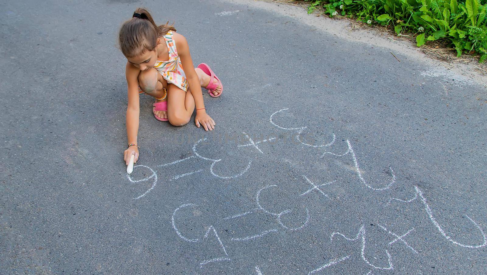 The child is doing chalk lessons on the asphalt. Selective focus. by yanadjana