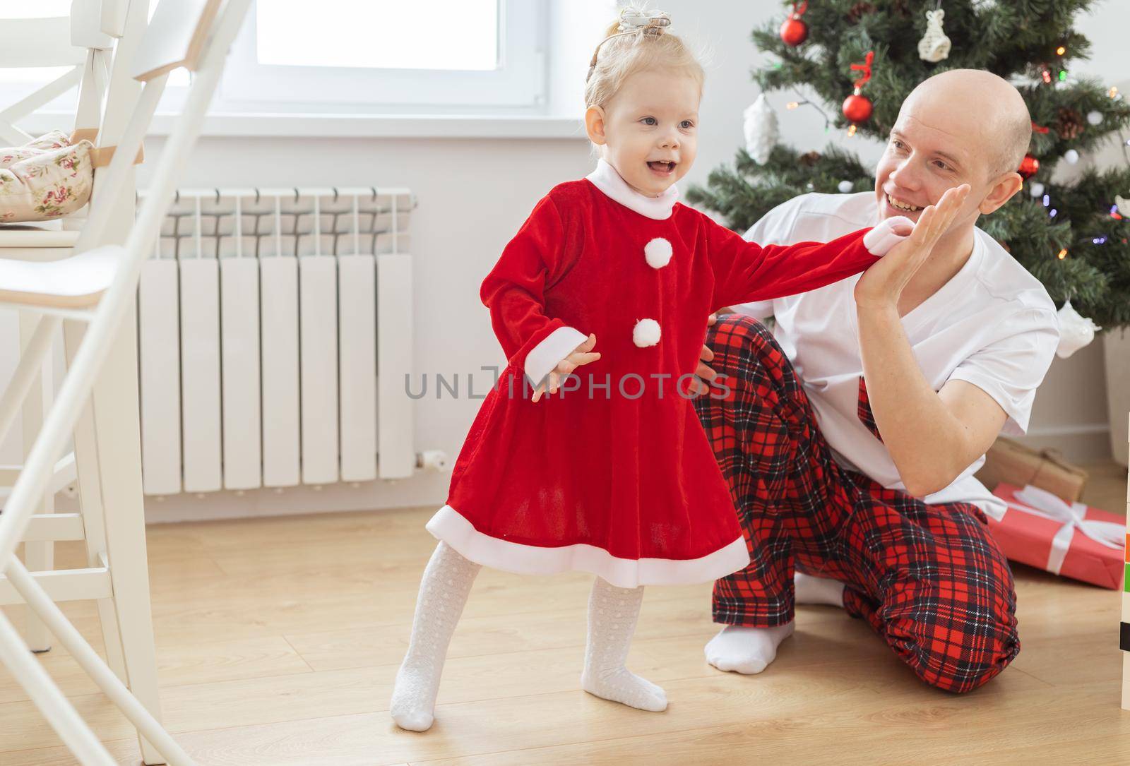 Toddler child with cochlear implant plays with father under christmas tree - deafness and innovating medical technologies for hearing aid by Satura86