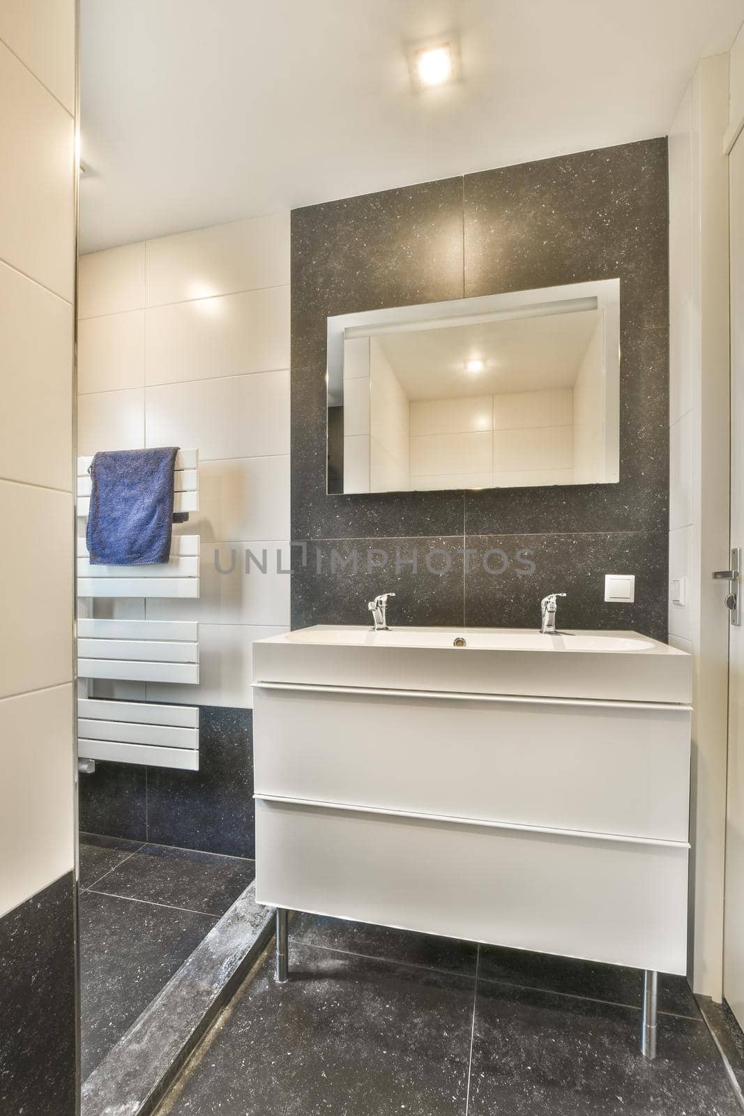 Modern sink in open bathroom with gray tiled wall and window