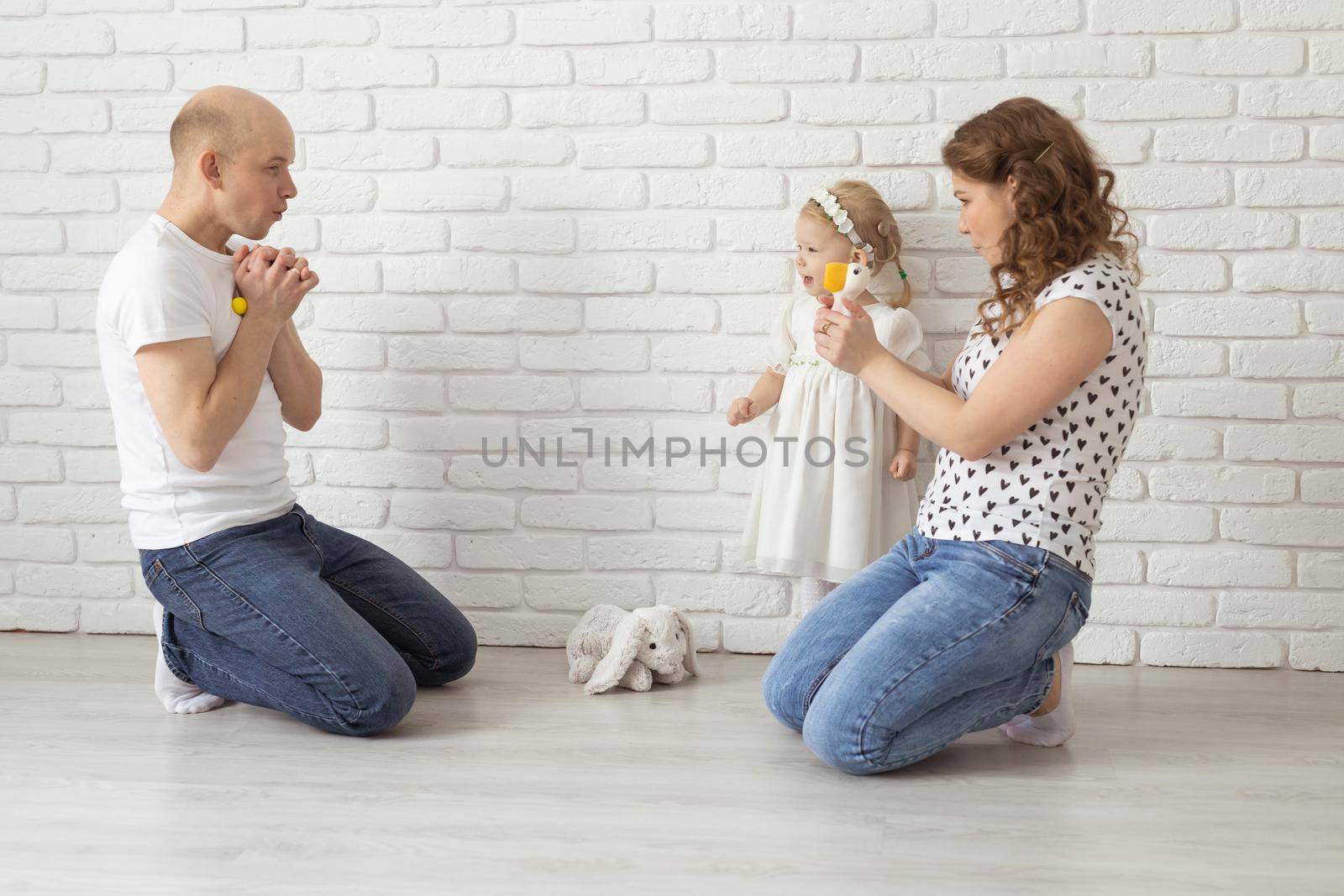 Baby child with hearing aids and cochlear implants plays with parents on floor. Deaf and rehabilitation and diversity concept by Satura86