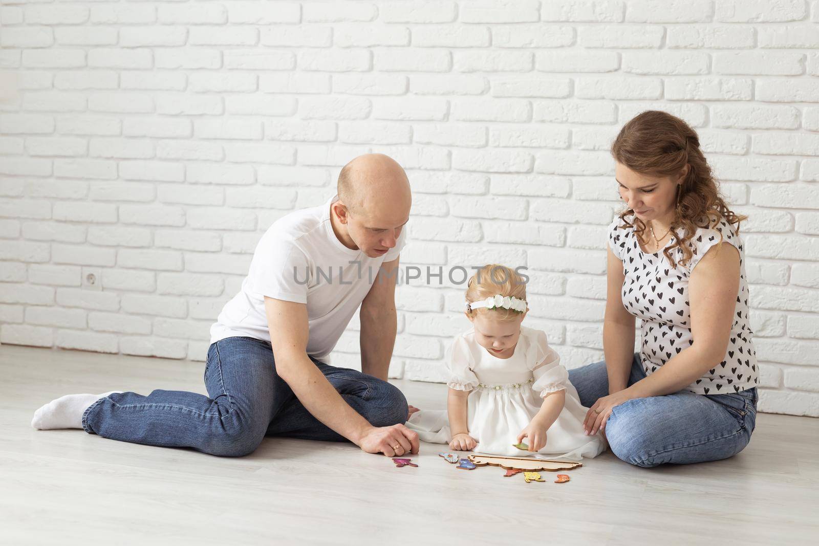 Baby child with hearing aids and cochlear implants plays with parents on floor. Deaf and rehabilitation and diversity concept by Satura86