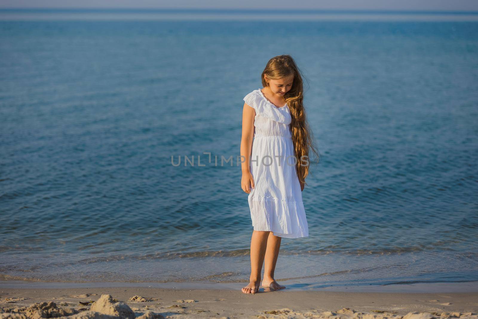 girl in white dress walking on the beach