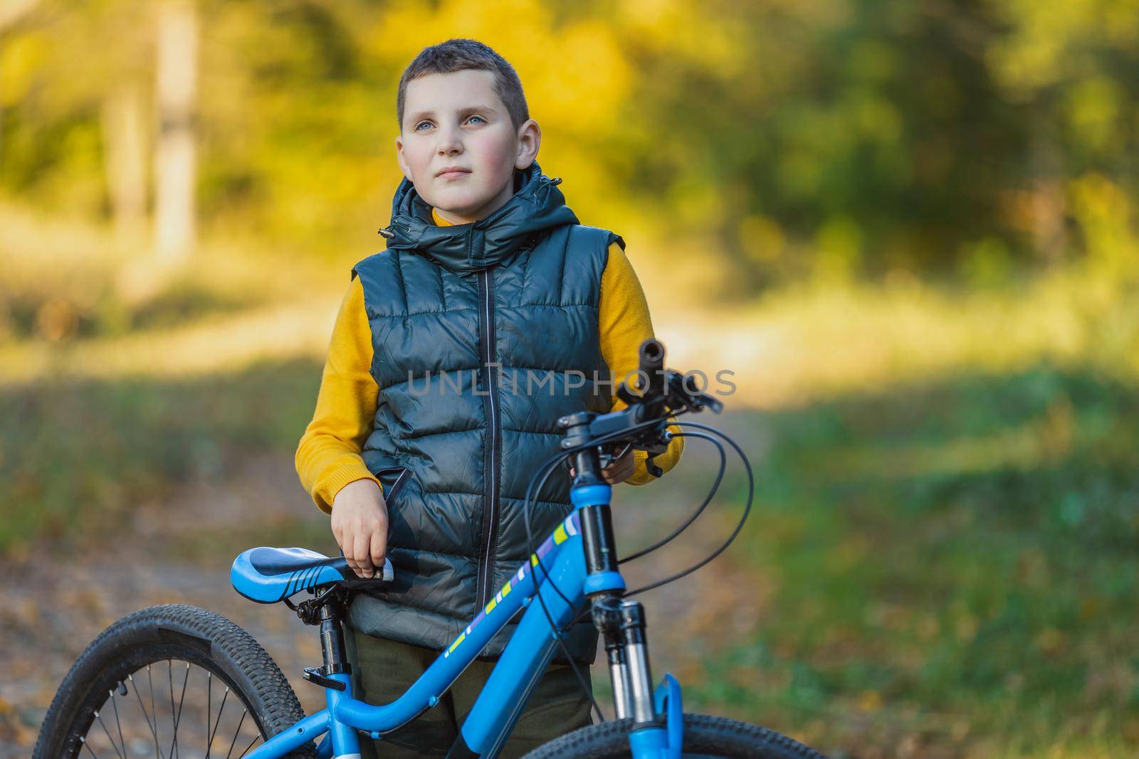 portrait of a boy with a bicycle against the background of an autumn forest