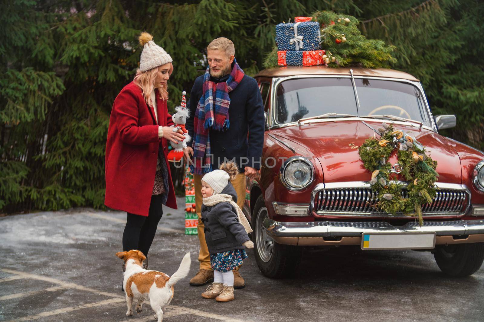 family near retro car with gifts in the parking lot near the park