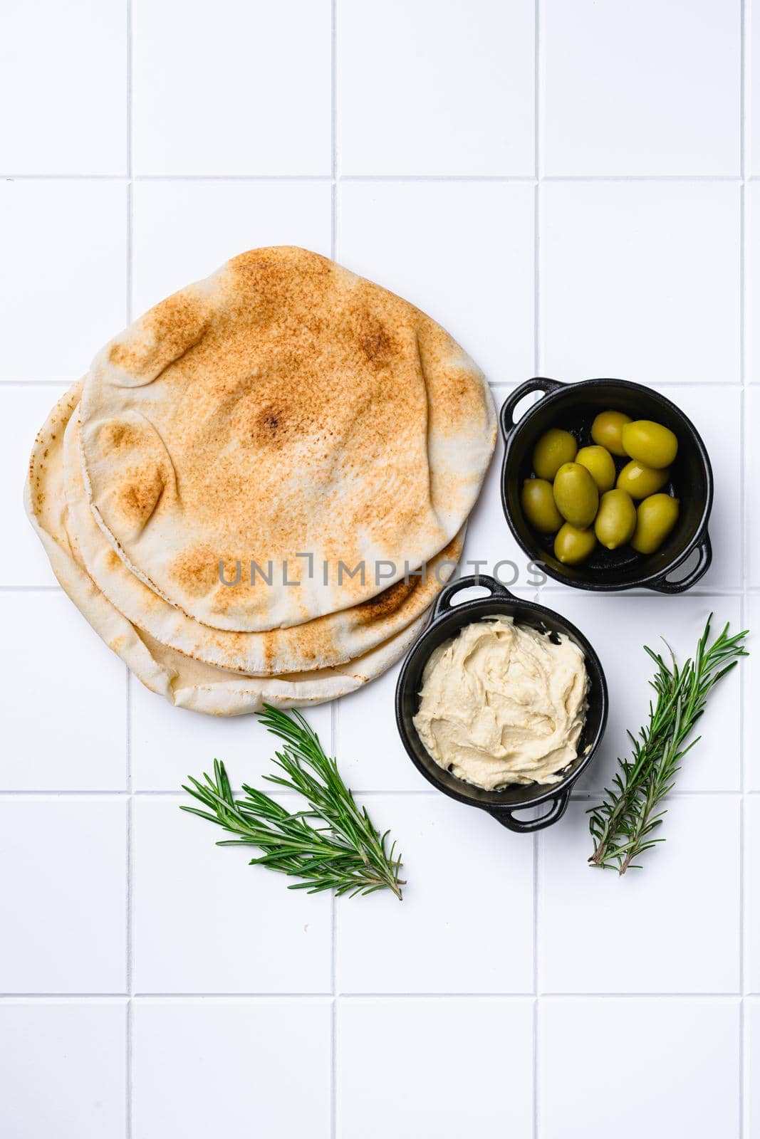 Hummus and pita bread set, on white ceramic squared tile table background, top view flat lay, with copy space for text by Ilianesolenyi