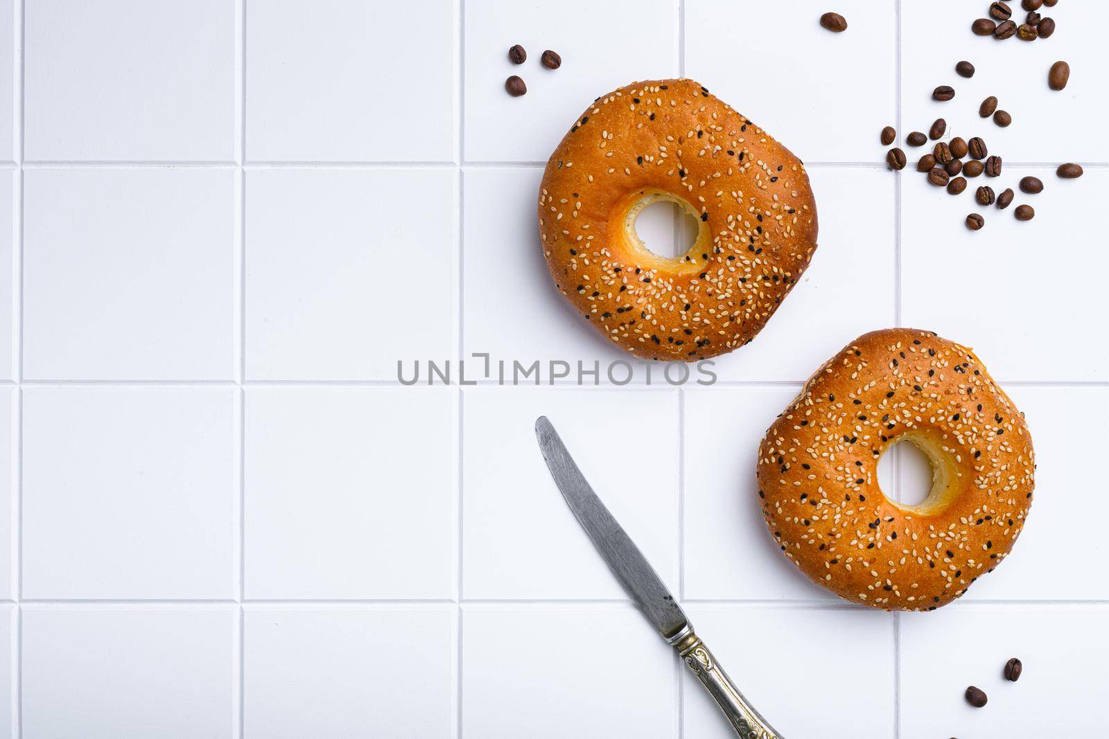 Fresh Sesame Bagel set, on white ceramic squared tile table background, top view flat lay, with copy space for text by Ilianesolenyi