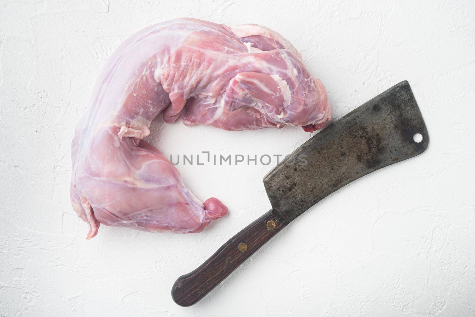 Fresh raw rabbit meat, and old butcher cleaver knife, on white stone background by Ilianesolenyi