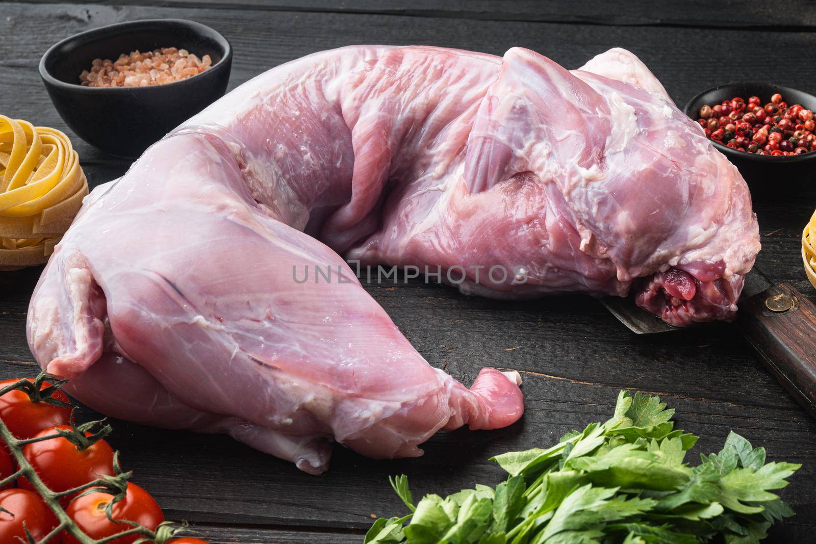 Whole rabbit, Raw meat with spices and vegetables for tagliatelle stewing set, on black wooden table background