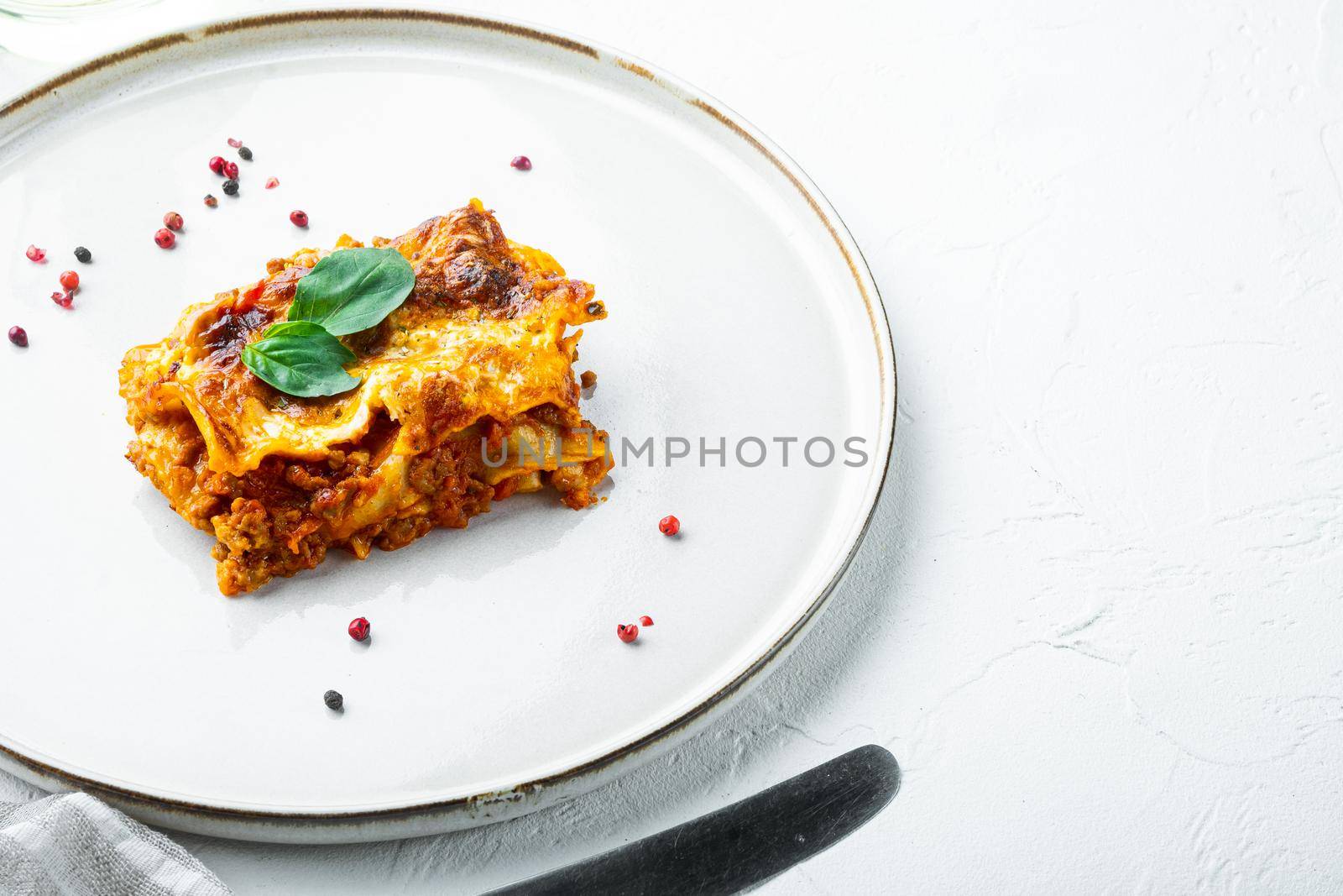 Italian Lasagne with tomato bolognese sauce and mince beef meat set, on plate, on white stone background, with copy space for text