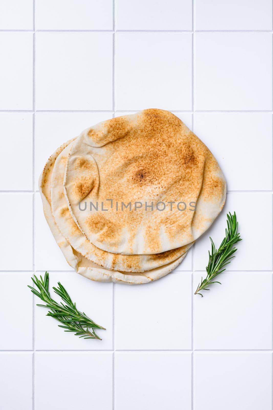 Freshly baked pita bread set, on white ceramic squared tile table background, top view flat lay, with copy space for text by Ilianesolenyi
