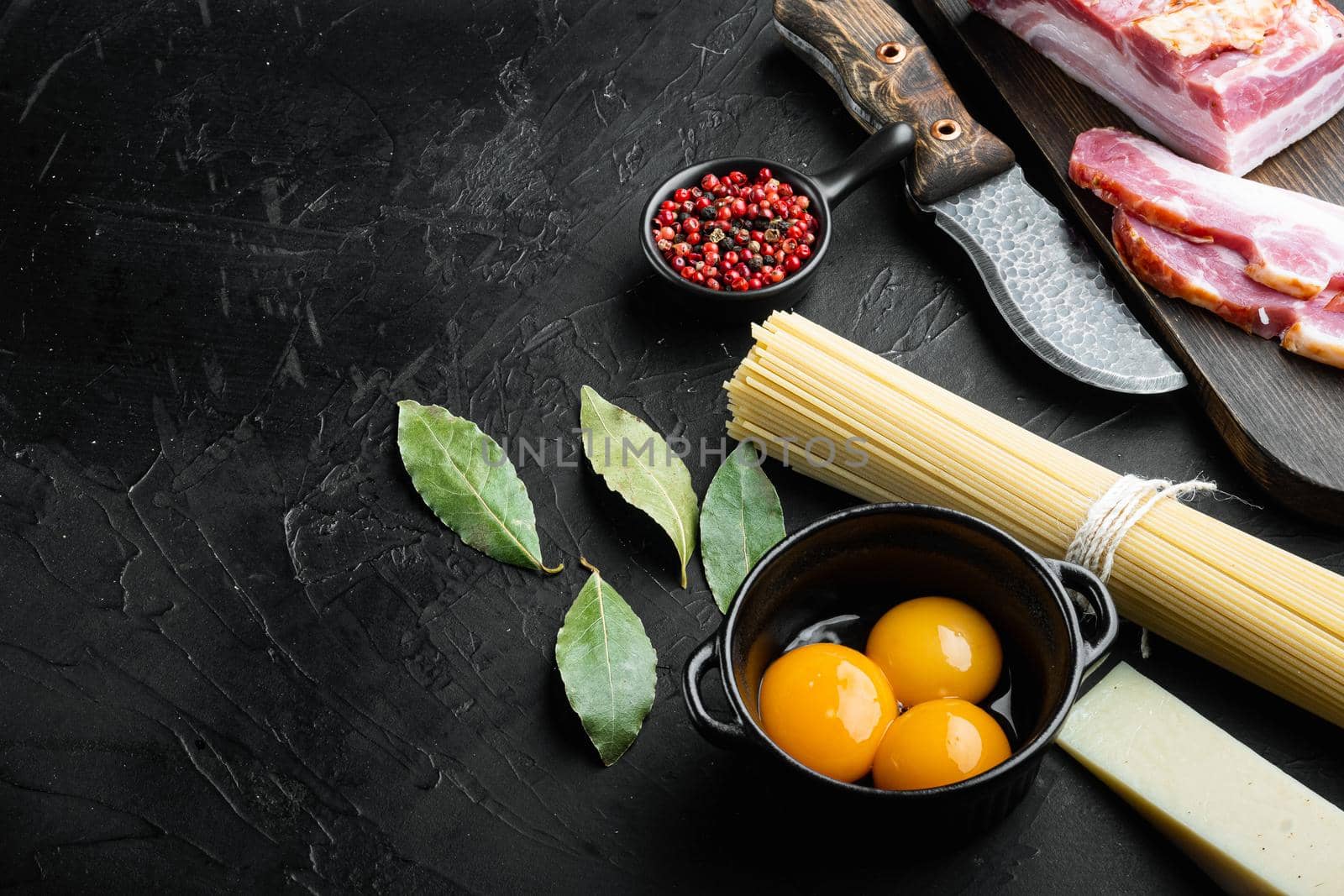 Cooking italian food collage. Ingredients for carbonara pasta, spaghetti, oil, ham, egg and parmesan set, on black stone background, with copy space for text