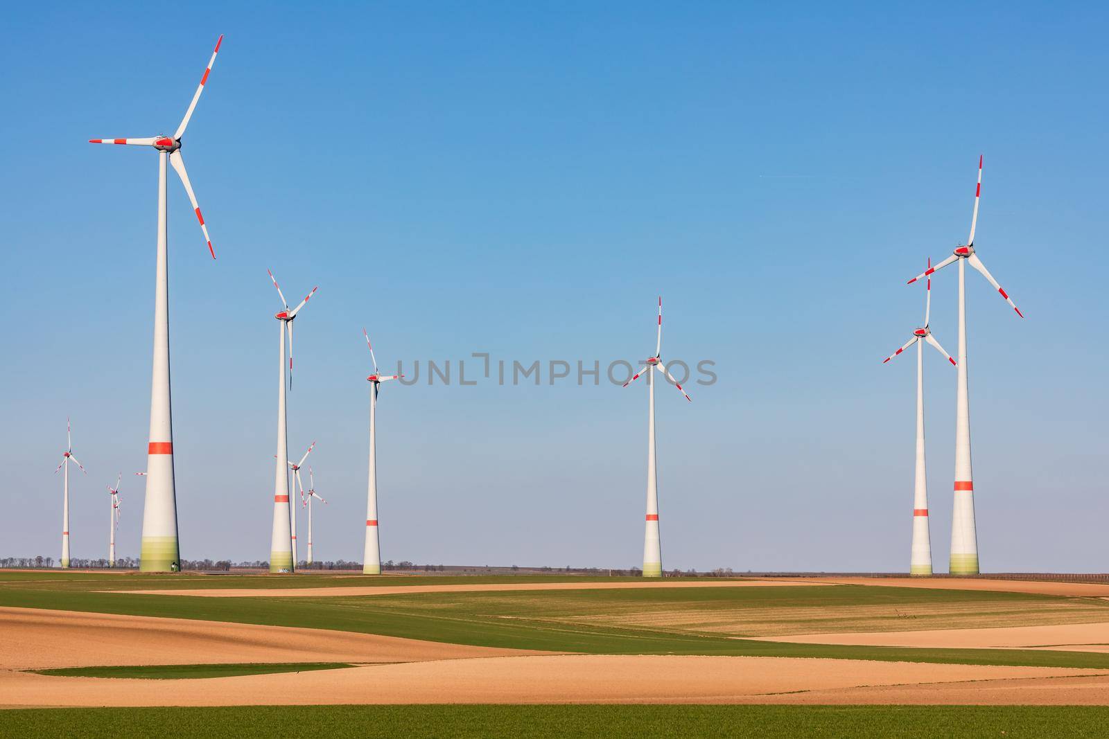 Massive towers of a wind farm dominate a rural landscape in Germany