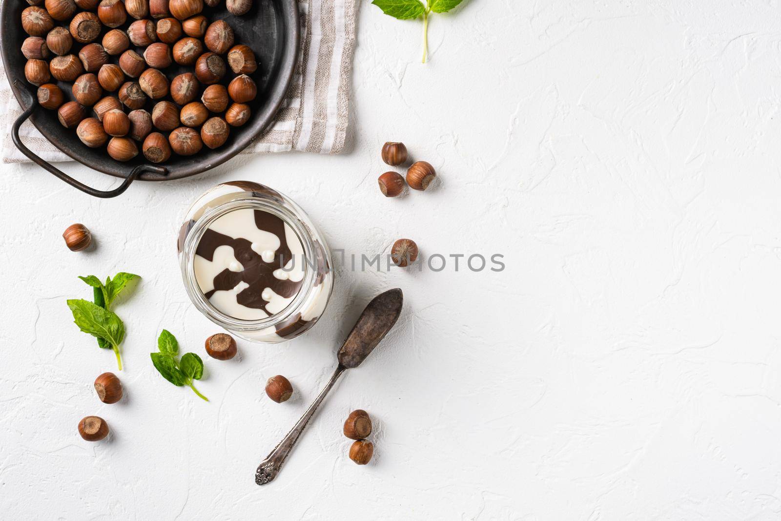 Chocolate hazelnut in jar with nuts set, on white stone table background, top view flat lay, with copy space for text