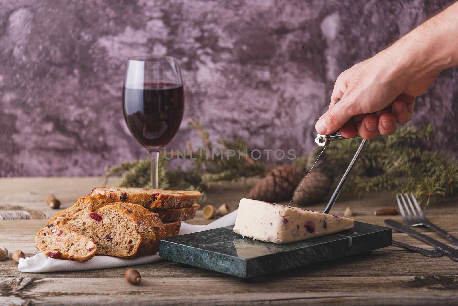 Wensleydale cheese with cranberries, red wine, honey, nuts, raisins on marble cutting board. Black concrete background. Selective focus