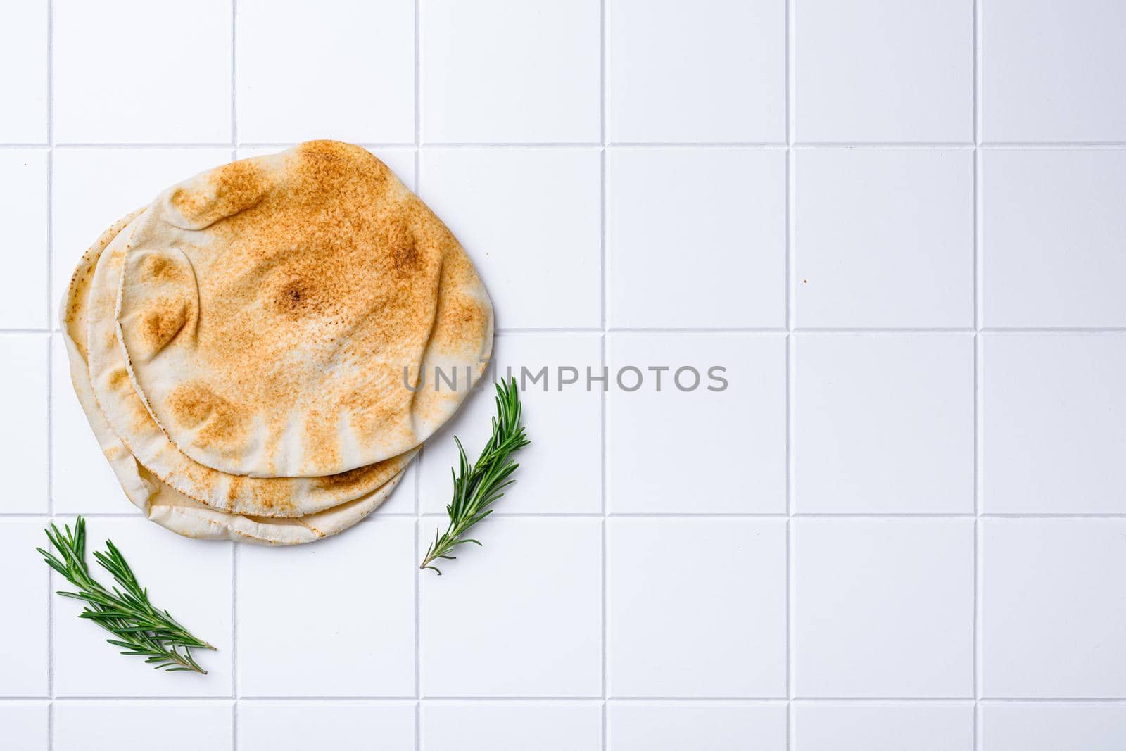 Pita flat bread, on white ceramic squared tile table background, top view flat lay, with copy space for text