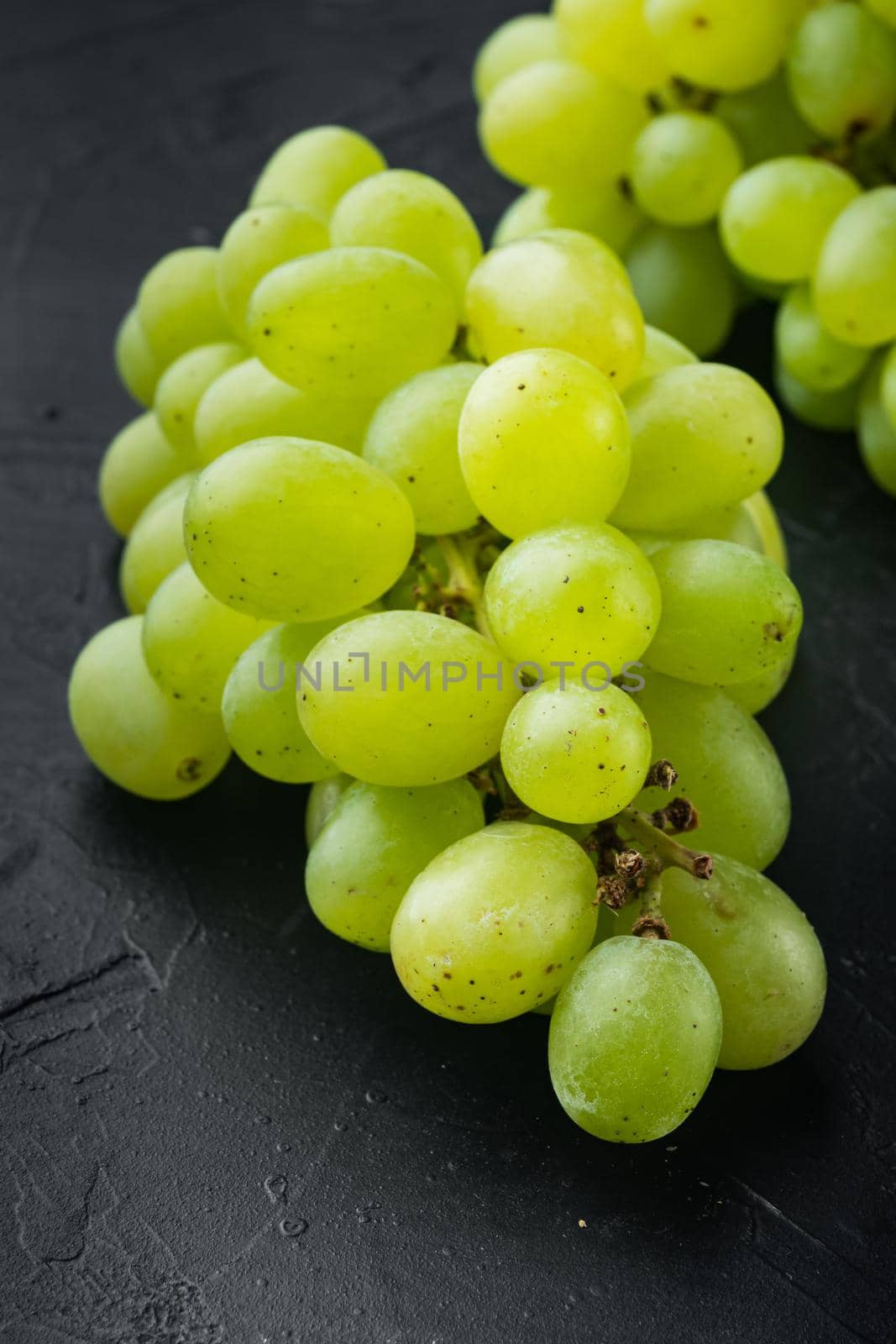 Red and white grapes set, green fruits, on black stone background