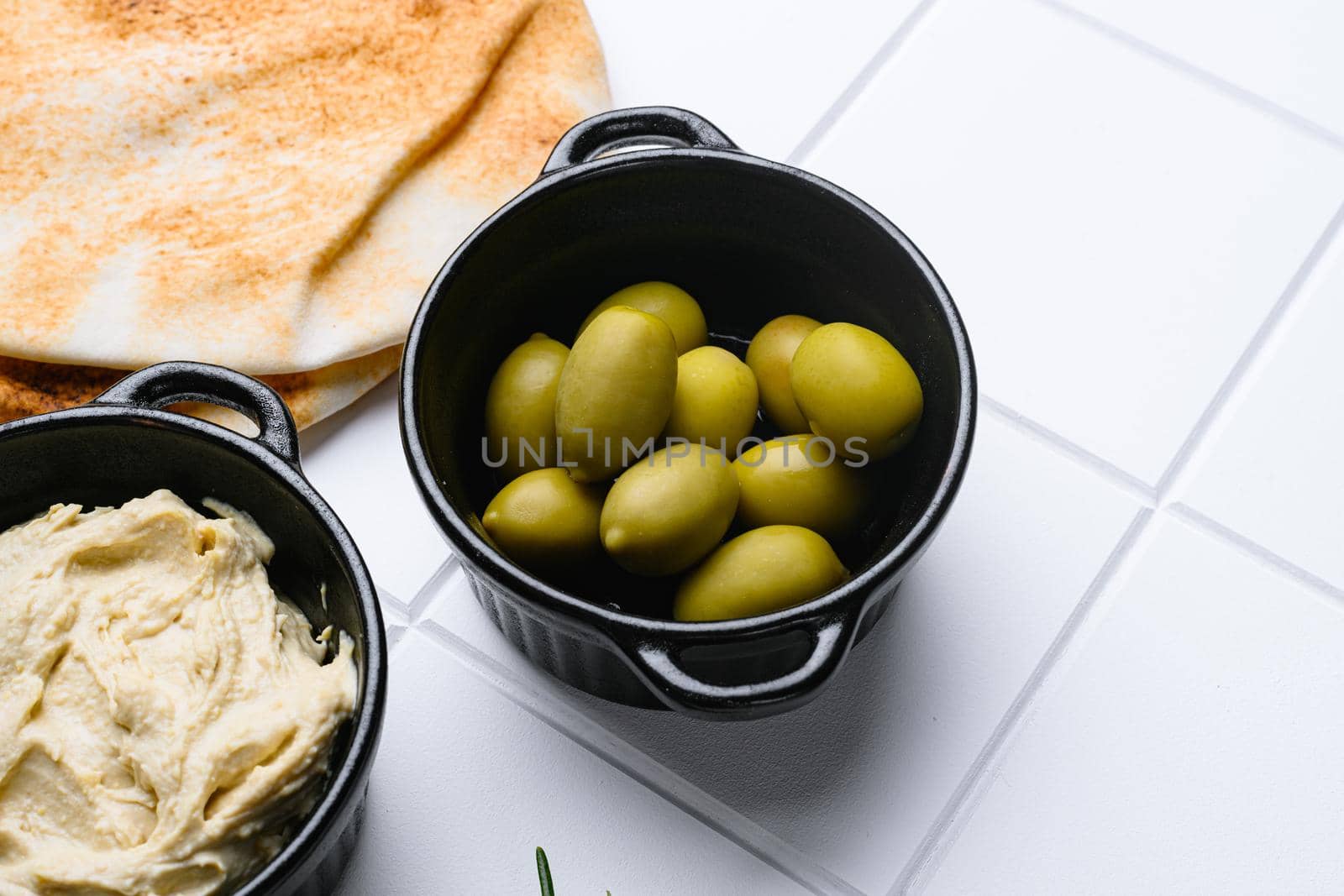 Greek green olives, on white ceramic squared tile table background, with copy space for text