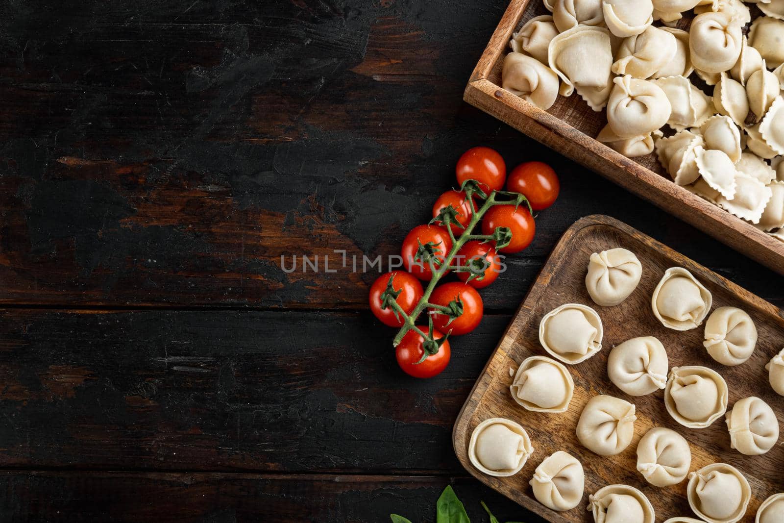 Raw Italian ravioli tortellini with fresh parmesan and basil , tomatoes on old dark wooden table background , top view flat lay , with copyspace and space for text by Ilianesolenyi
