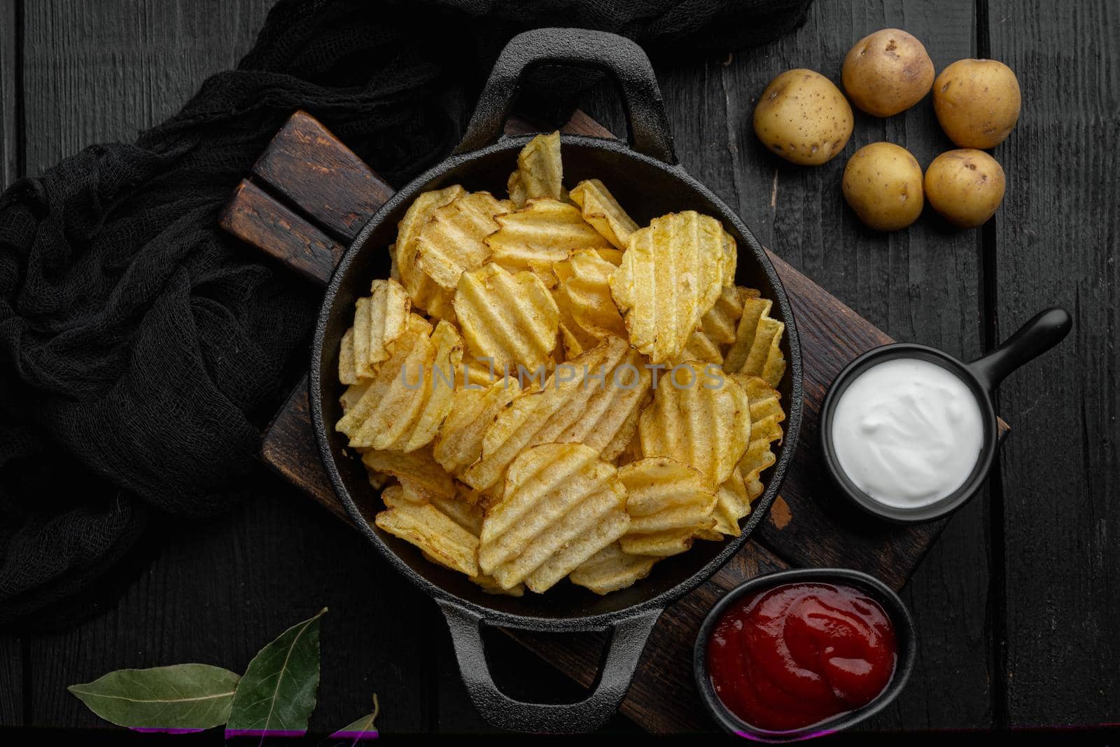 Crispy potato chips set, on black wooden background, top view flat lay