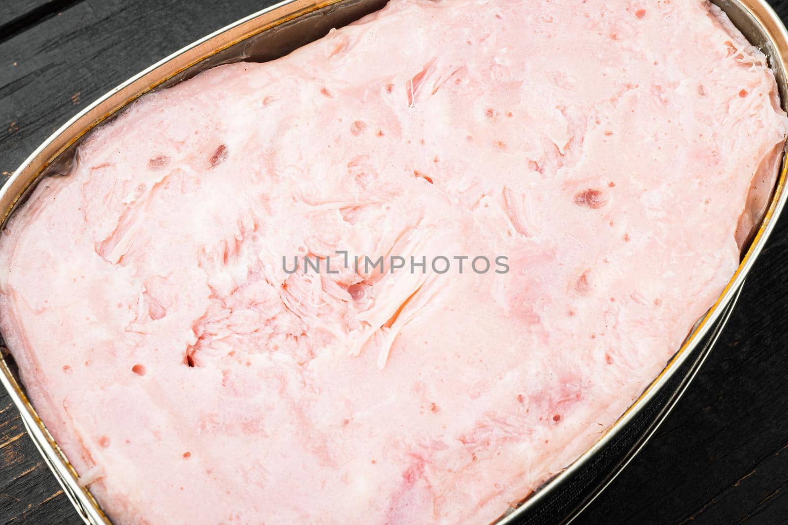 Ham in tin can set, on black wooden table background