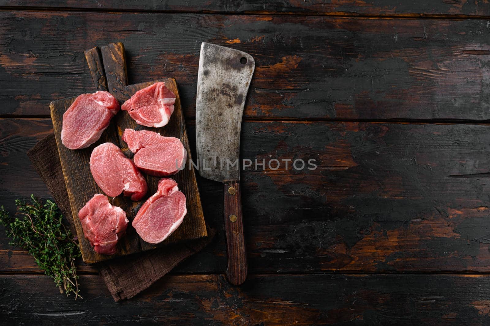 Raw pork medallion steaks, on old dark wooden table background, top view flat lay, with copy space for text