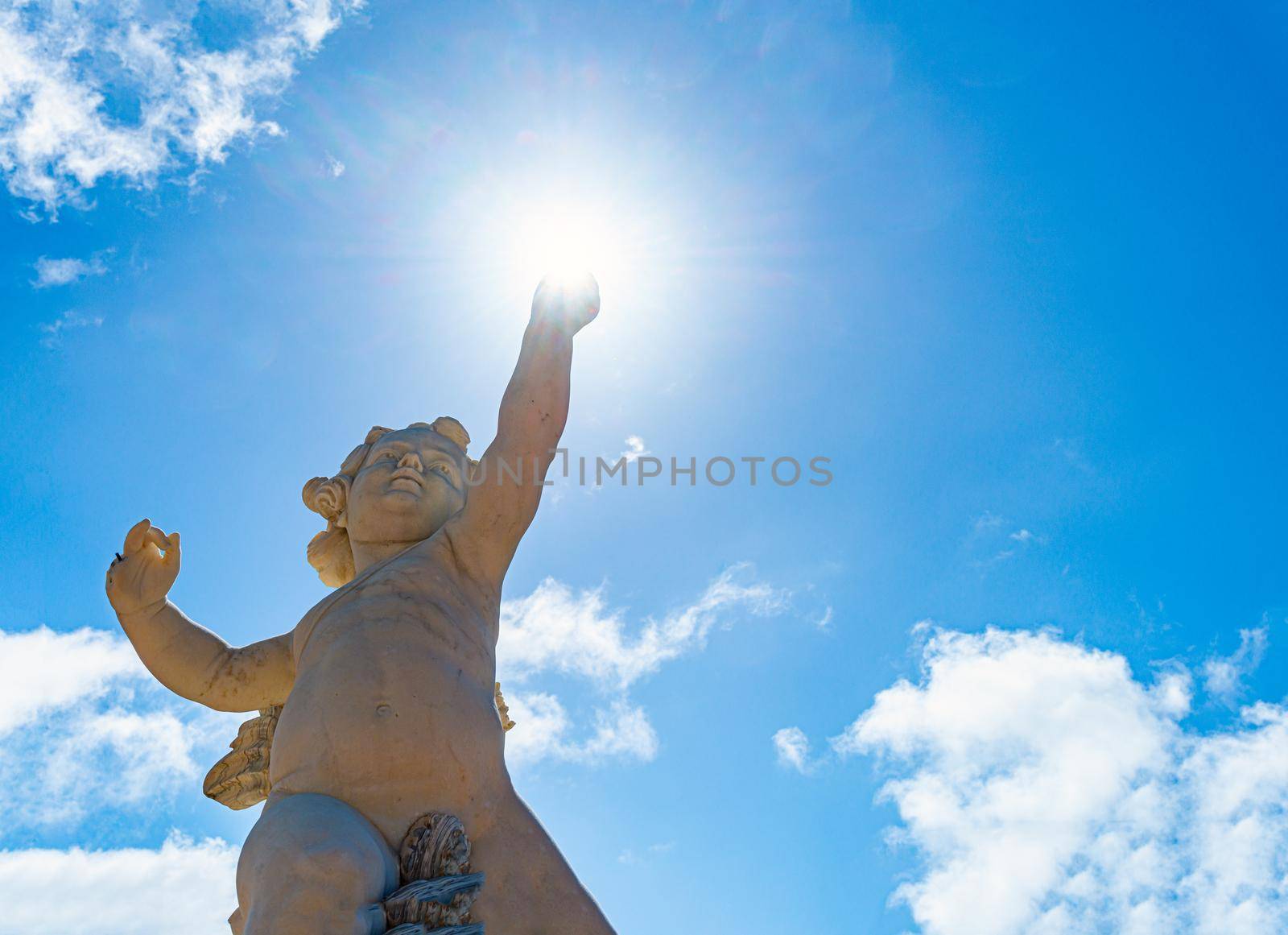Statue of angel boy with cloudy sky in background