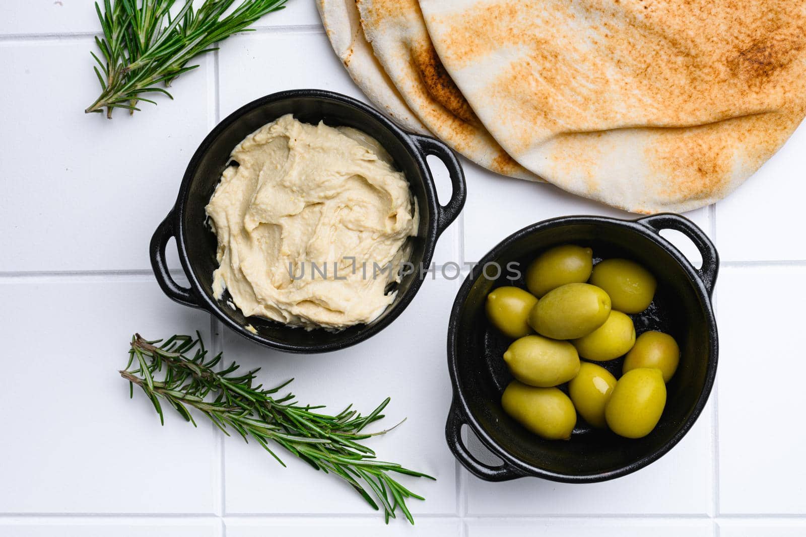 Hummus and wheat flatbread, on white ceramic squared tile table background, top view flat lay