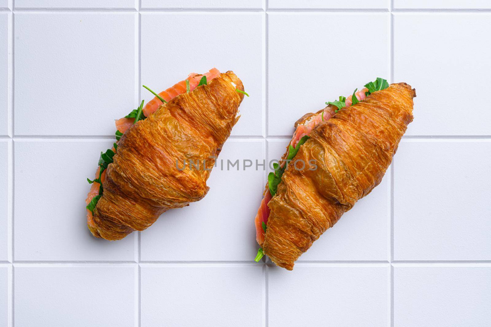 Croissant sandwich with salmon set, on white ceramic squared tile table background, top view flat lay