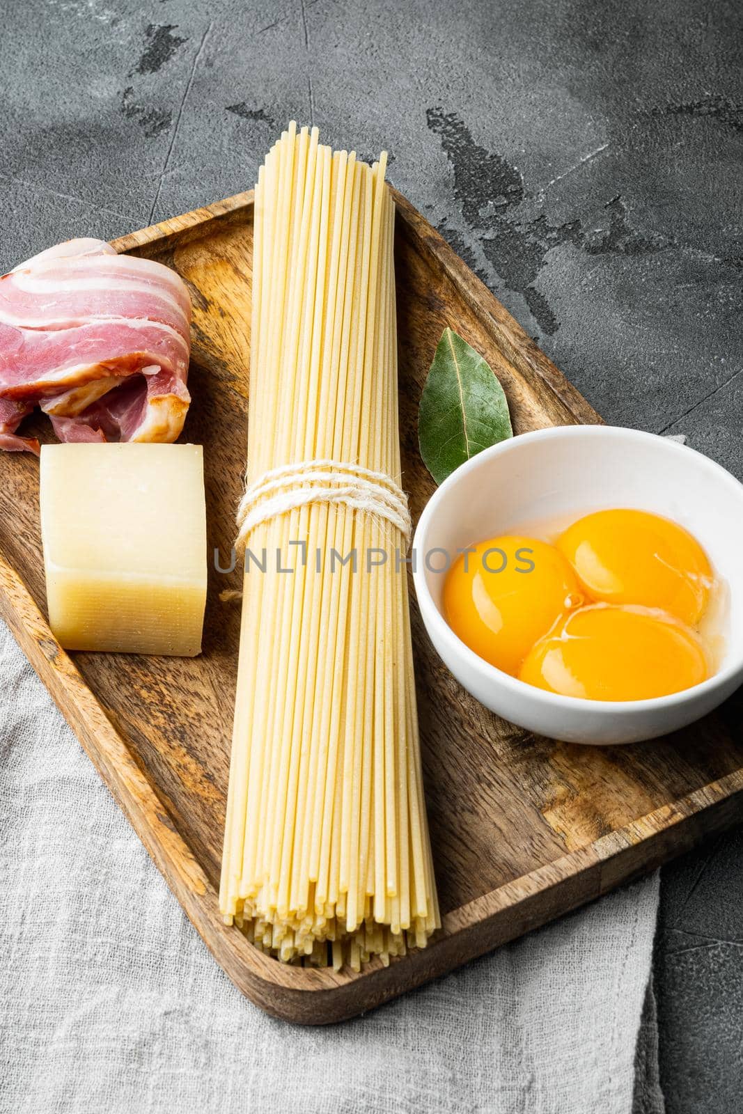 Fresh raw ingredients for traditional italian pasta Carbonara, on gray stone background by Ilianesolenyi