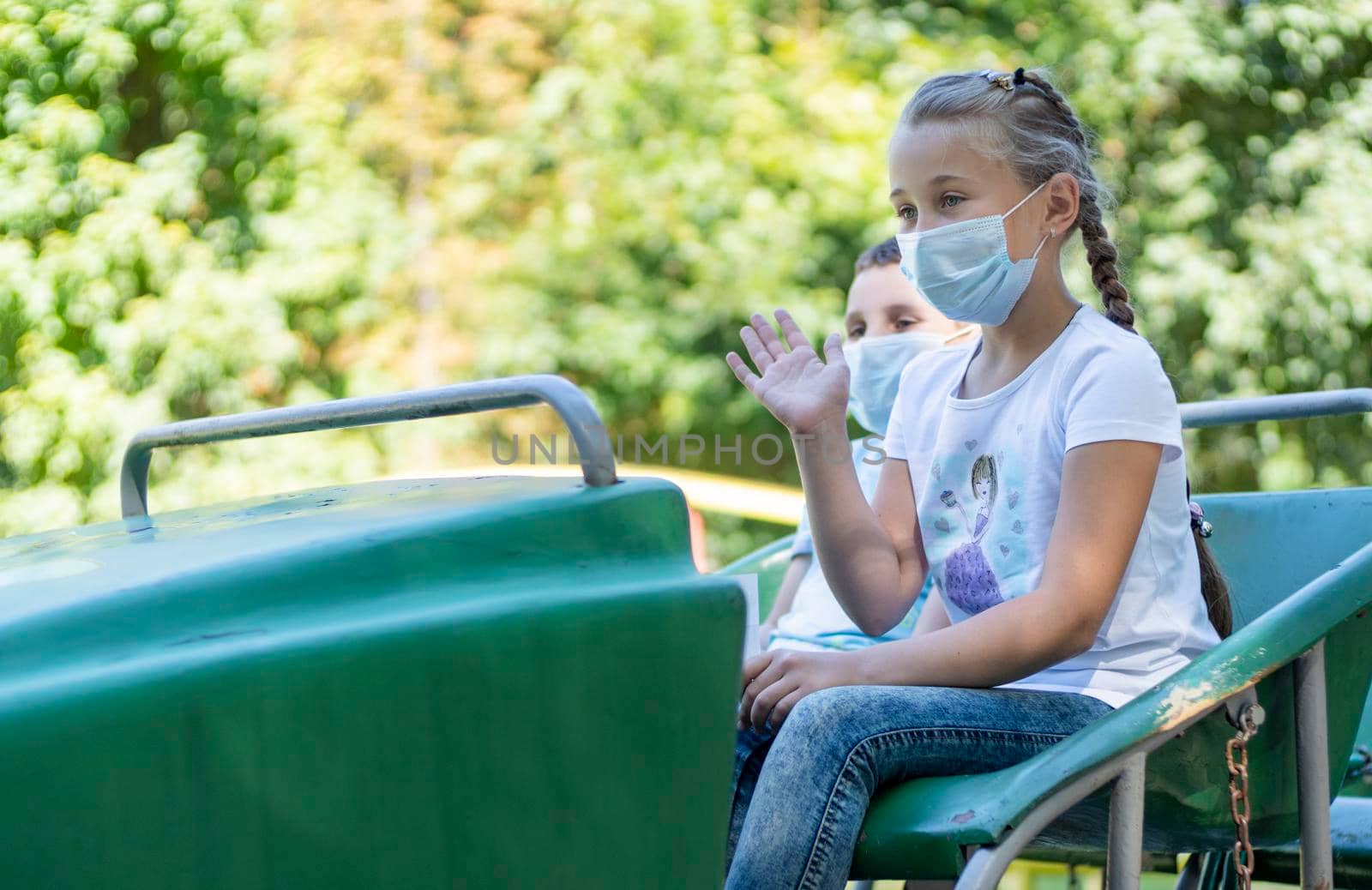 children in medical masks ride an attraction train