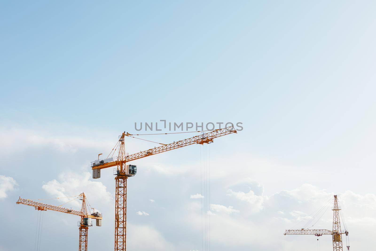 building cranes at the construction site on blue sky background by nikkytok