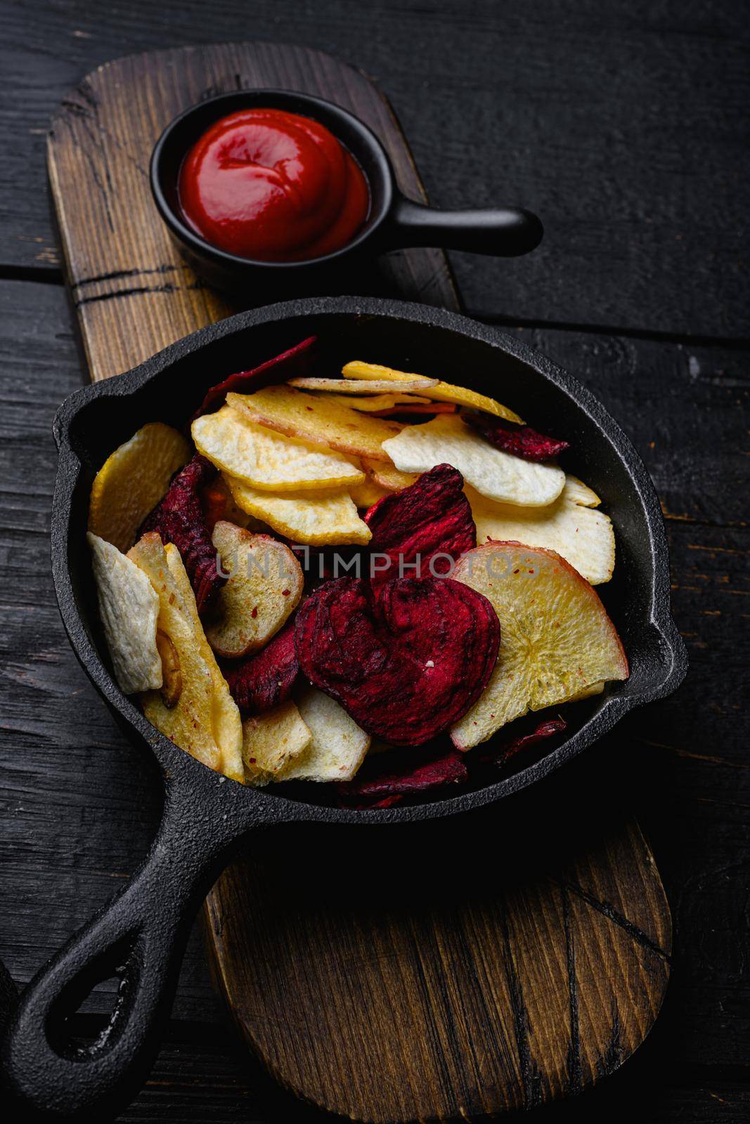 Dried vegetables chips, on black wooden table background by Ilianesolenyi