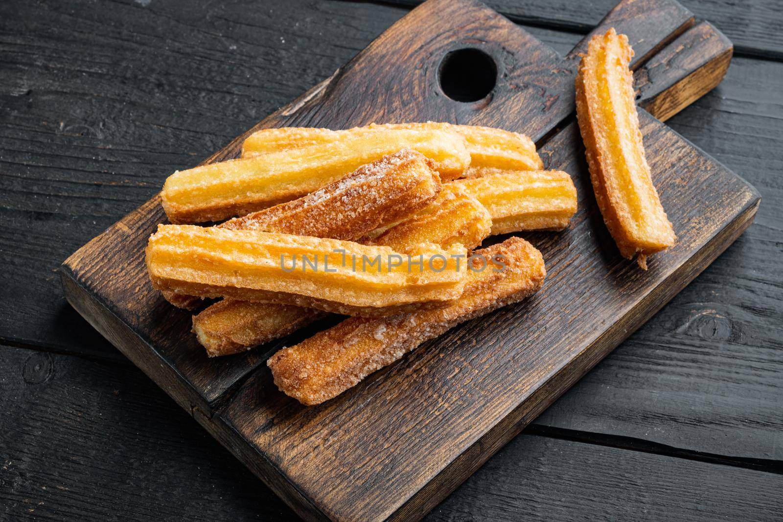 Tasty churros with chocolate caramel sauce, on black wooden table background by Ilianesolenyi