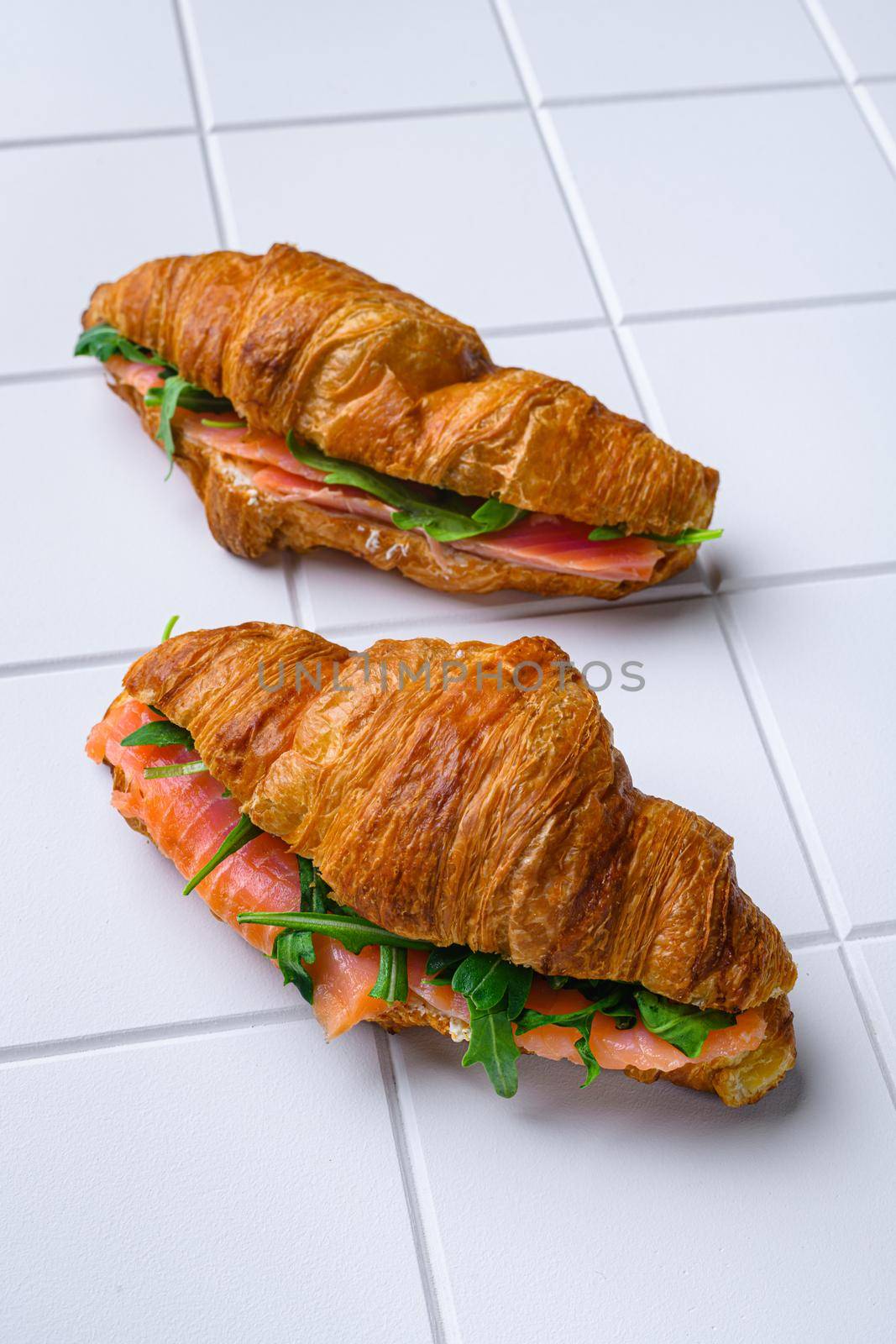 Croissant with salmon and cream cheese set, on white ceramic squared tile table background