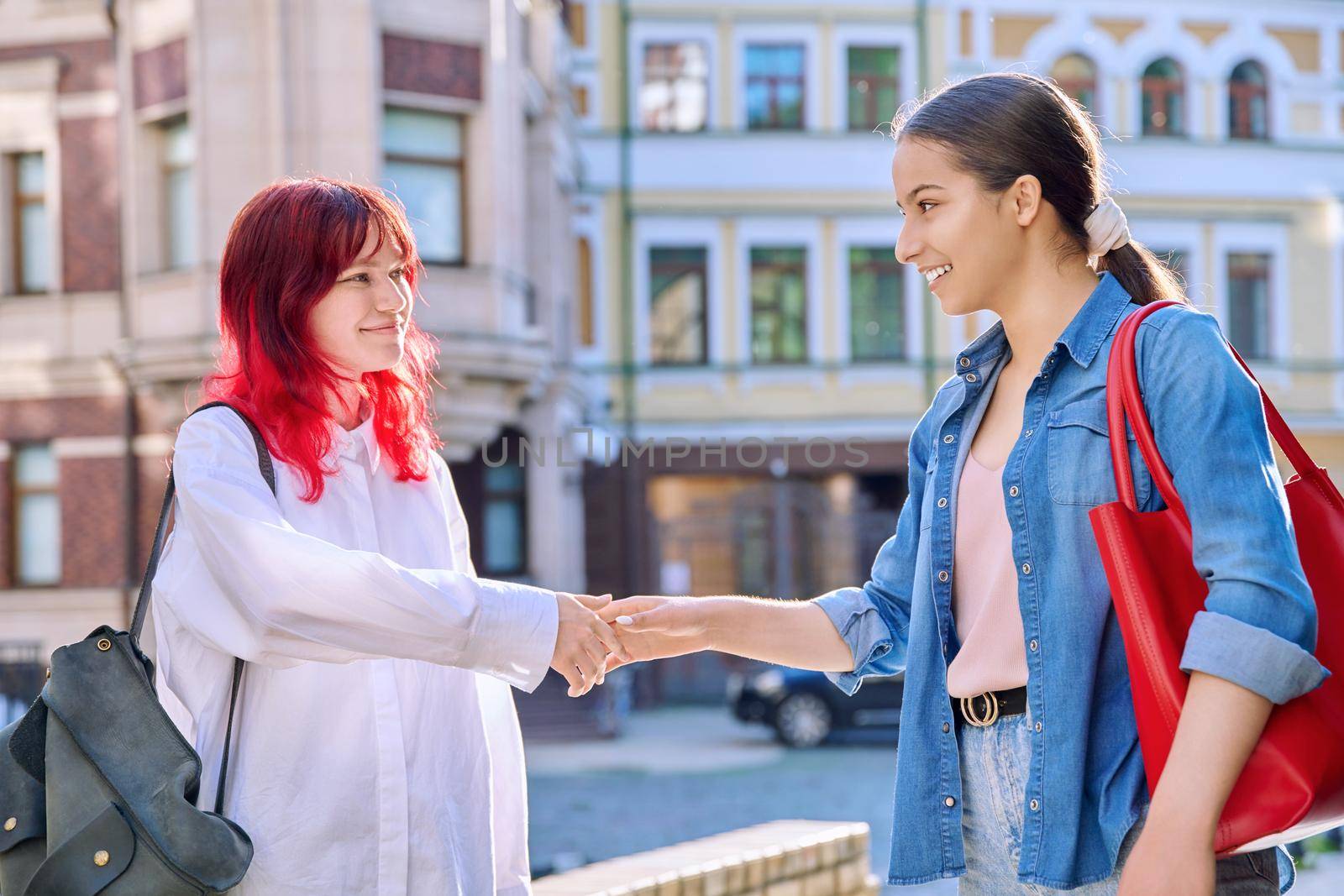 Meeting of two teenage girls friends, outdoor on the city street by VH-studio