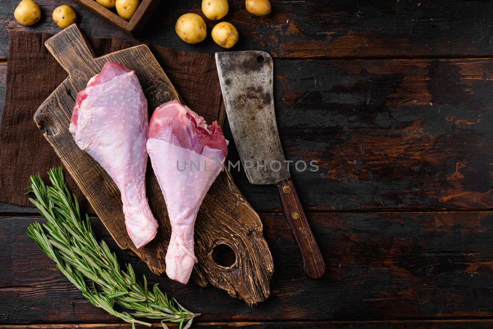 Fresh turkey legs with ingredients for cooking set, on old dark wooden table background, top view flat lay, with copy space for text