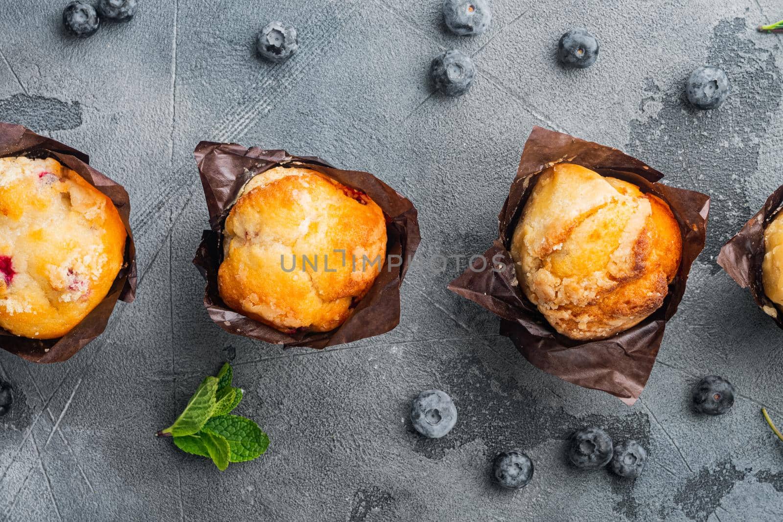 Homemade muffins with fresh blueberries, on gray background, top view flat lay by Ilianesolenyi