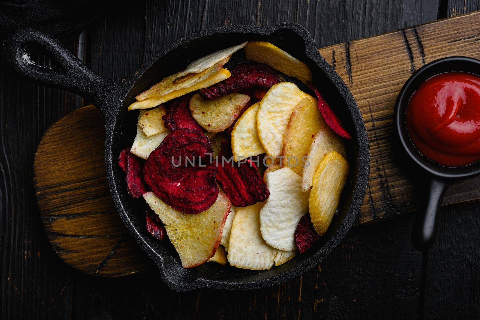 Dried vegetables chips from carrot, beet, parsnip and other vegetables set, on black wooden table background, top view flat lay