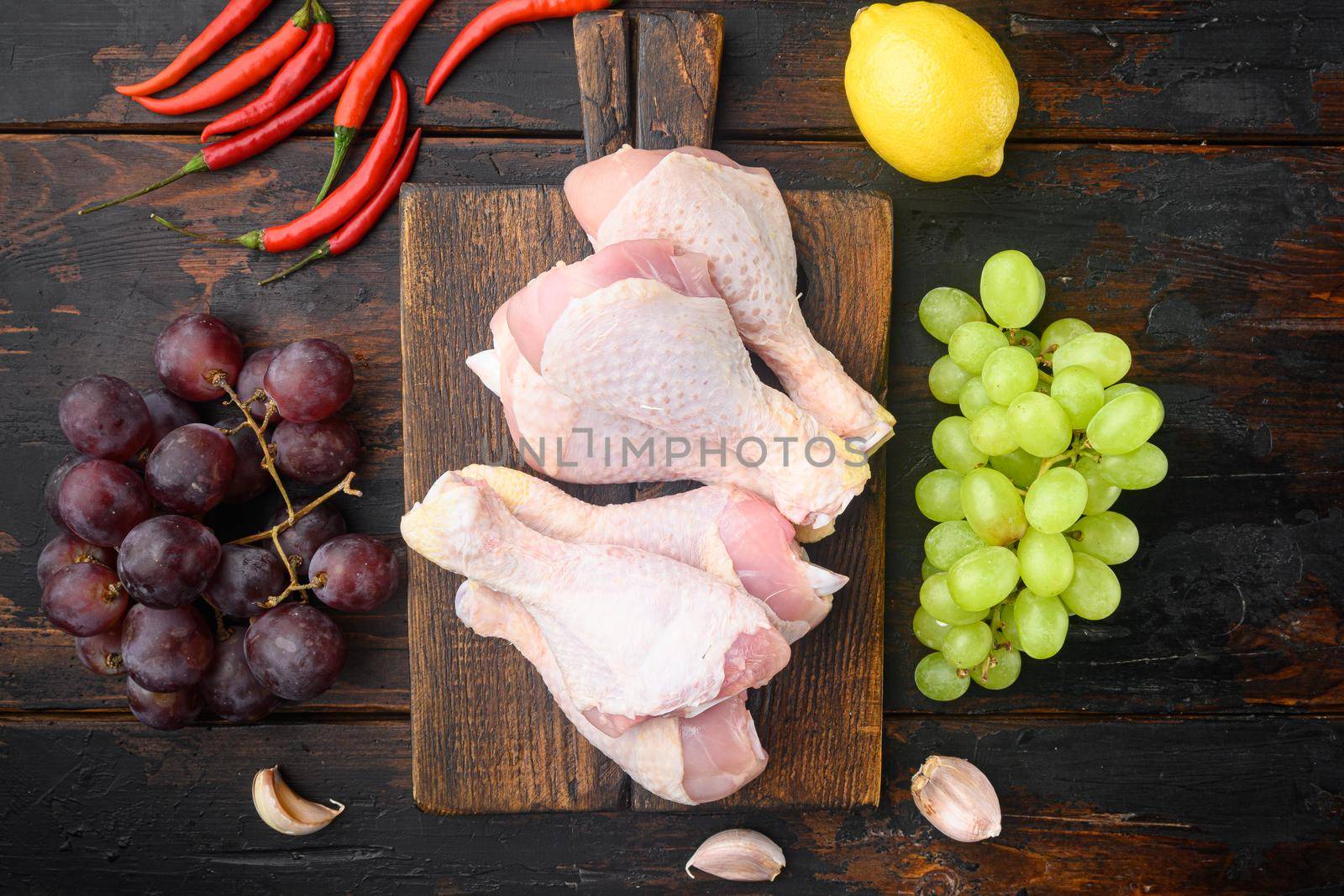 Sweet chicken surprise ingredients set, with grape and parsley, on wooden cutting board, on old dark wooden table, top view flat lay