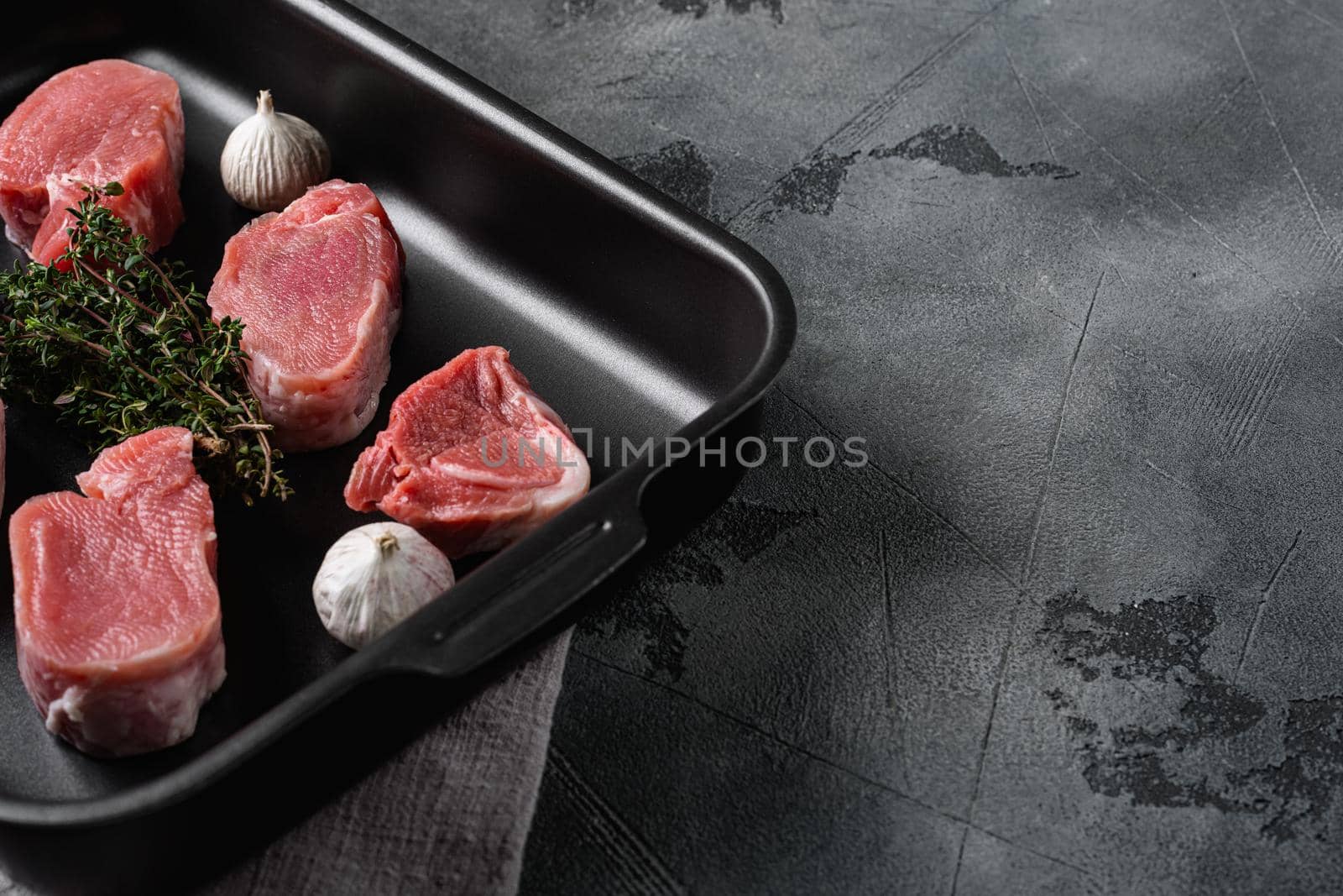 Raw pork fillet with spices, on gray stone table background, with copy space for text