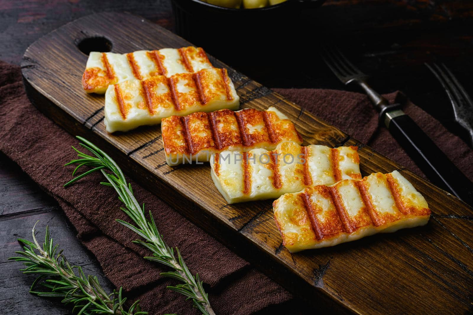 Grilling Halloumi Cheese, on old dark wooden table background by Ilianesolenyi