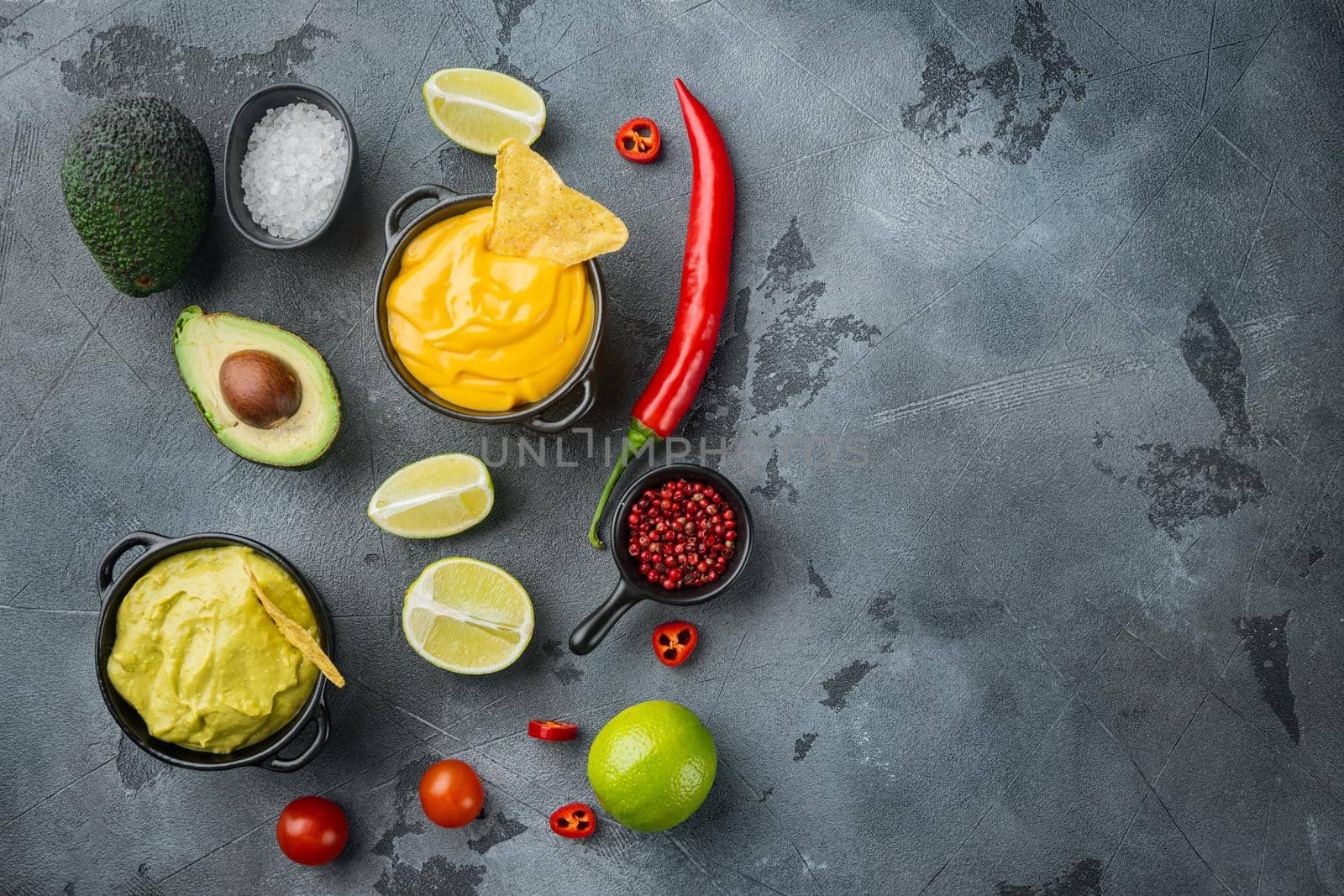 Green guacamole and yellow cheese dip sauce for traditional, Mexican tacos, on gray background, top view or flat lay with copy space for text