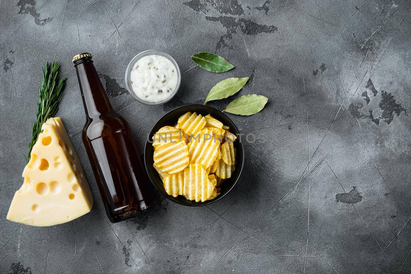 Potatoe chips with Cheese and Onion, with dipping sauces , and bottle of beer , on gray stone background, top view flat lay, with copy space for text by Ilianesolenyi