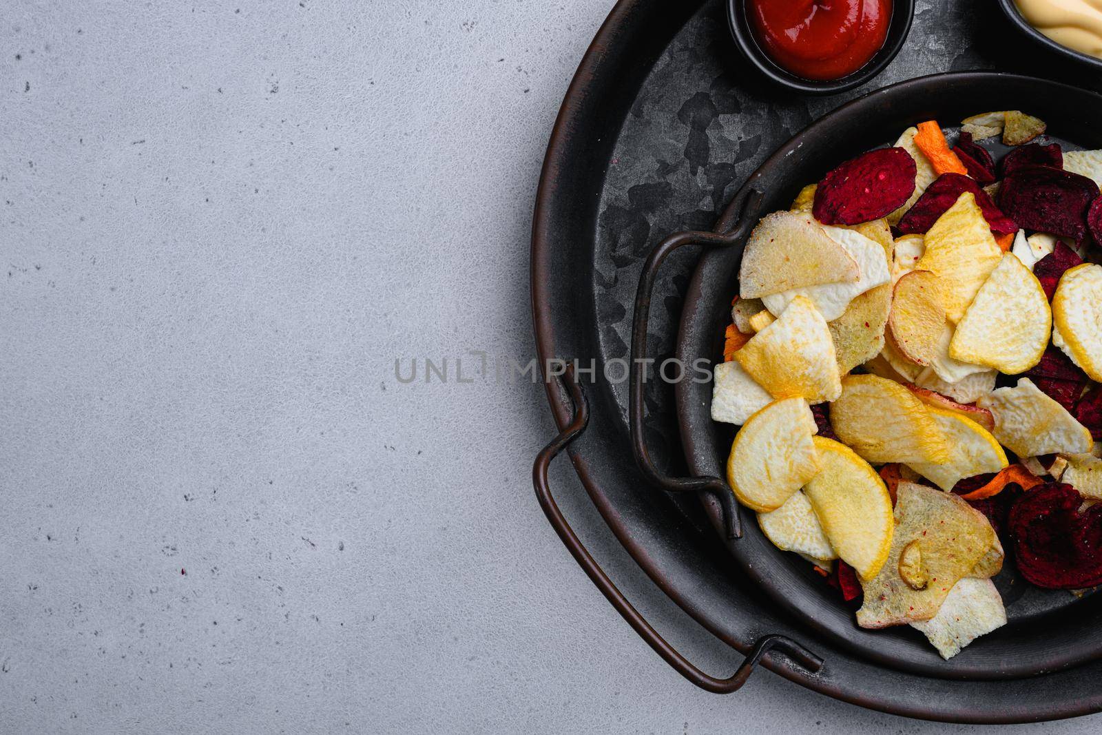 Dried vegetables chips from carrot, beet, parsnip and other vegetables, on gray stone table background, top view flat lay, with copy space for text by Ilianesolenyi