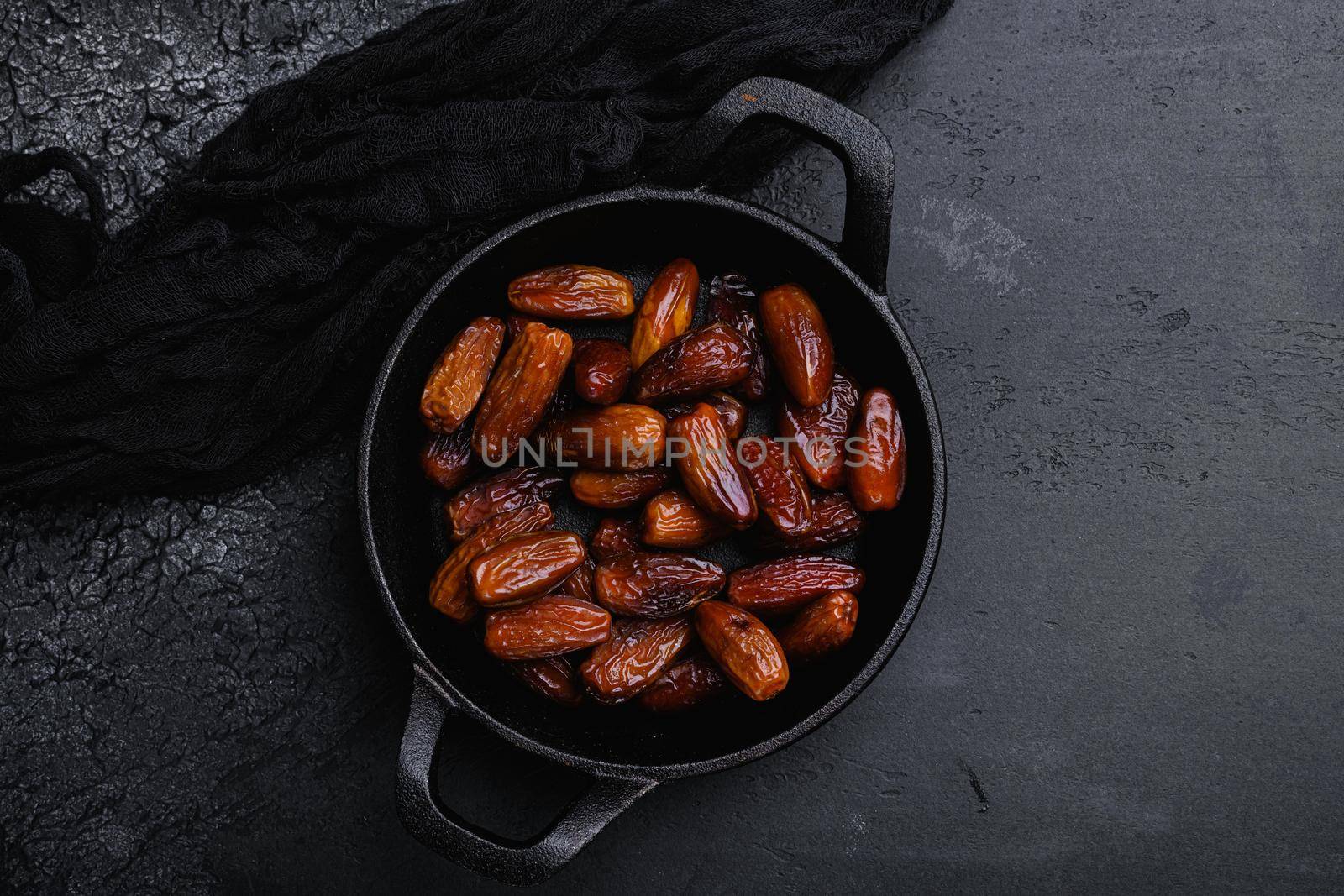 Dried date palm fruits, on black dark stone table background, top view flat lay, with copy space for text