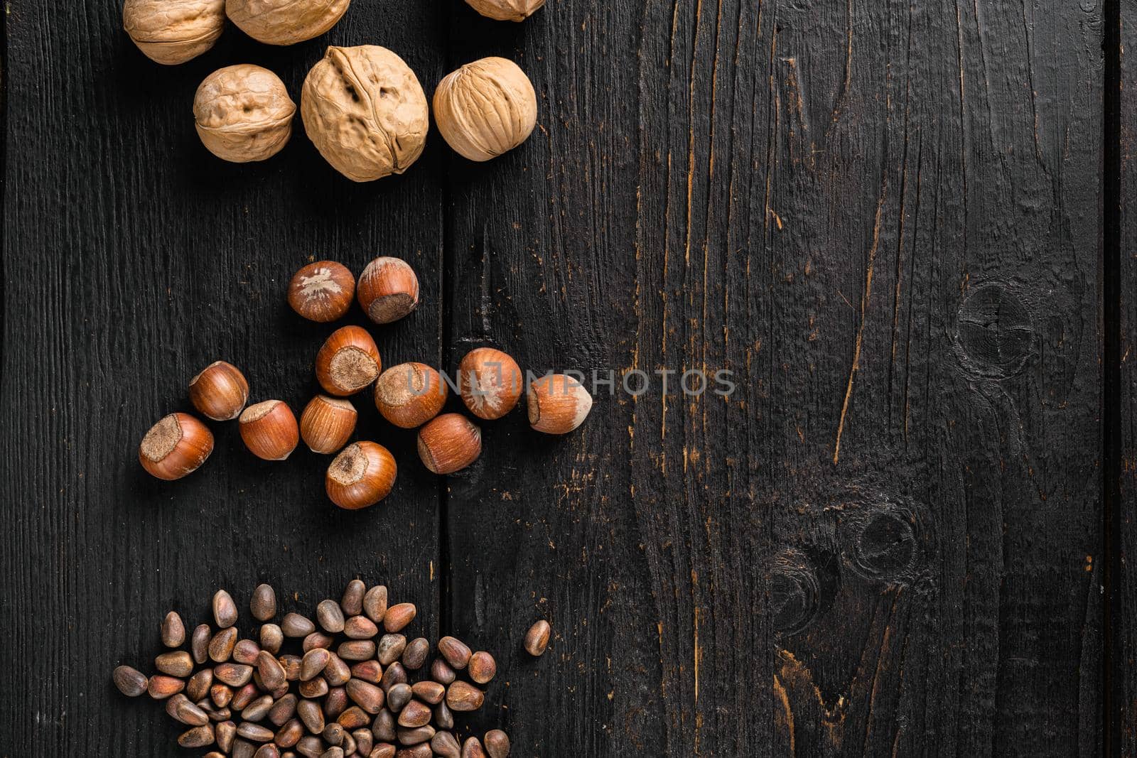 Heap or stack of hazelnuts set, on black wooden table background, top view flat lay, with copy space for text