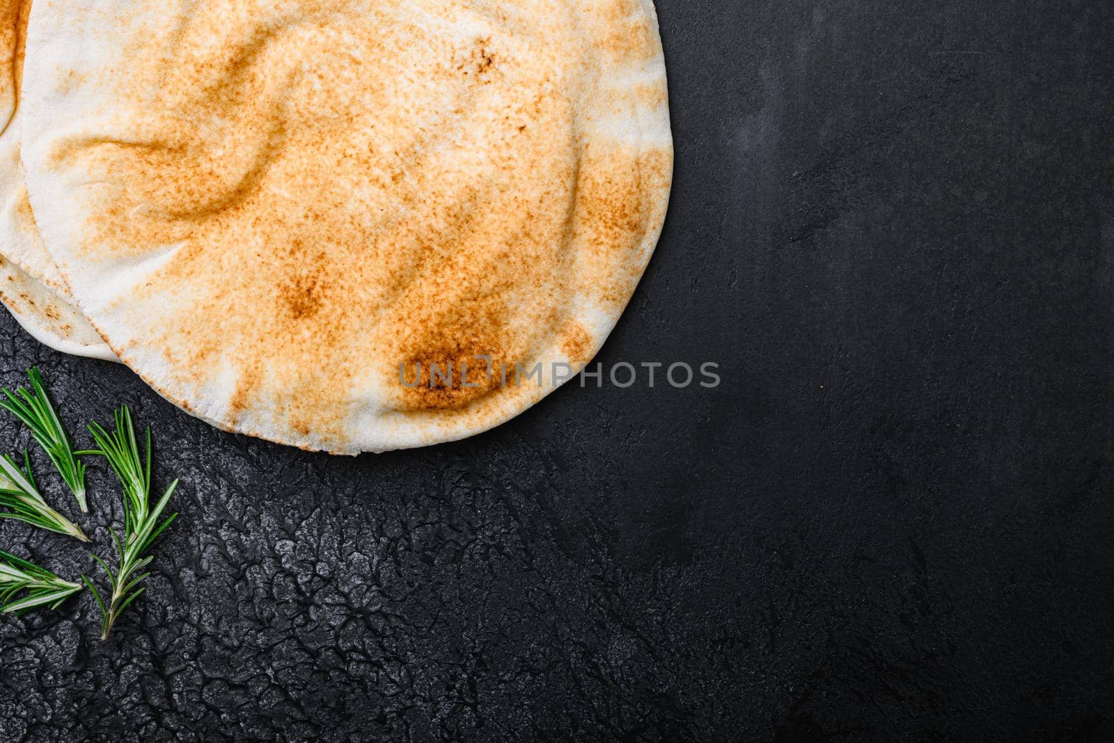 Freshly baked pita bread set, on black dark stone table background, top view flat lay, with copy space for text by Ilianesolenyi