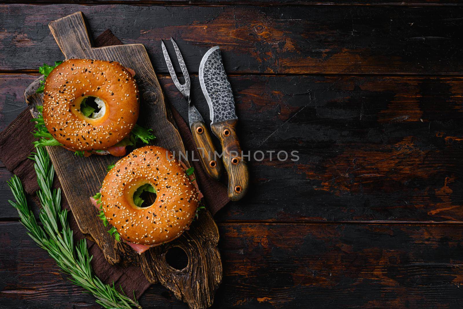 Bagel with red fish and soft cheese, on old dark wooden table background, top view flat lay, with copy space for text by Ilianesolenyi