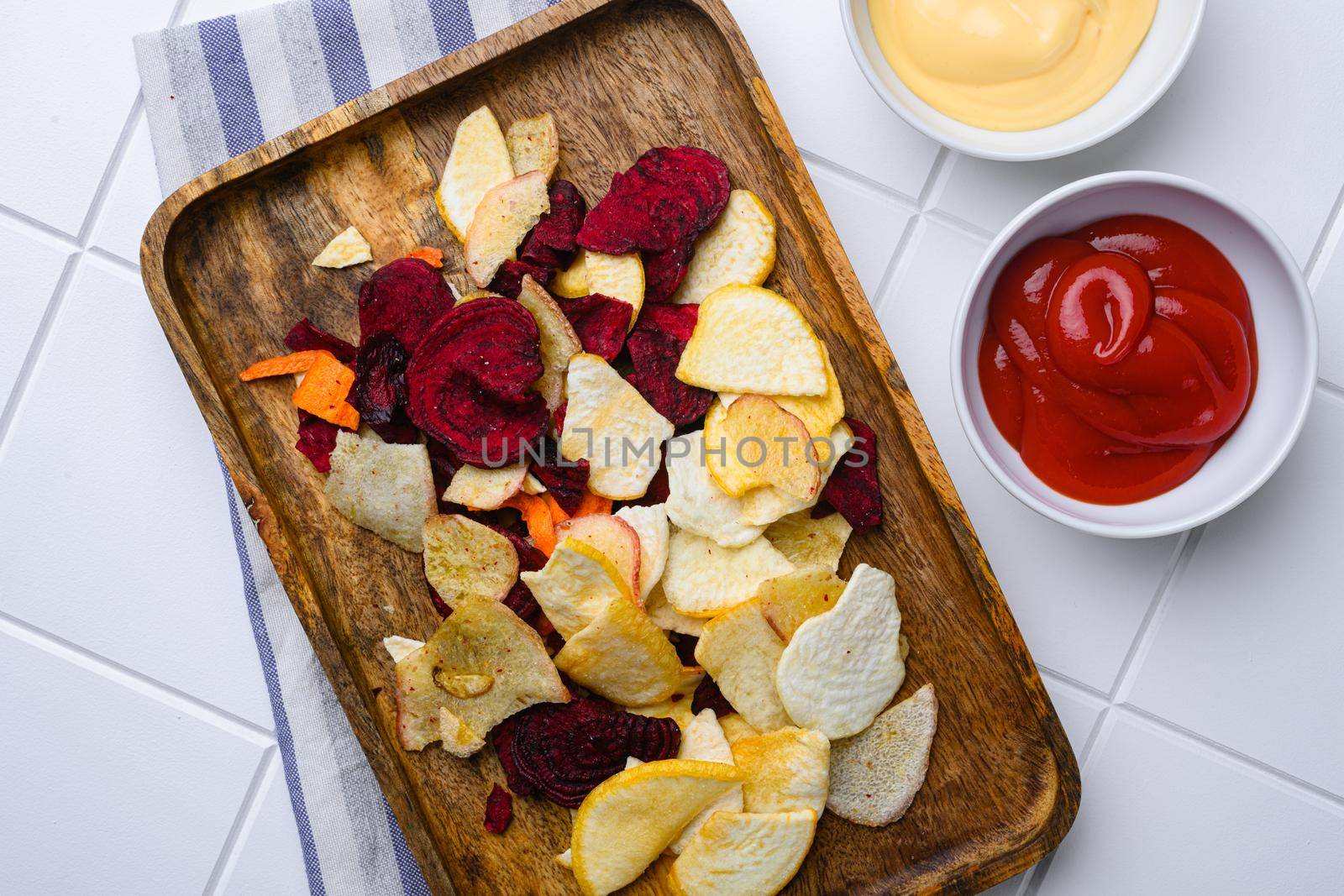 Beetroot carrot and turnip chips, on white ceramic squared tile table background, top view flat lay by Ilianesolenyi